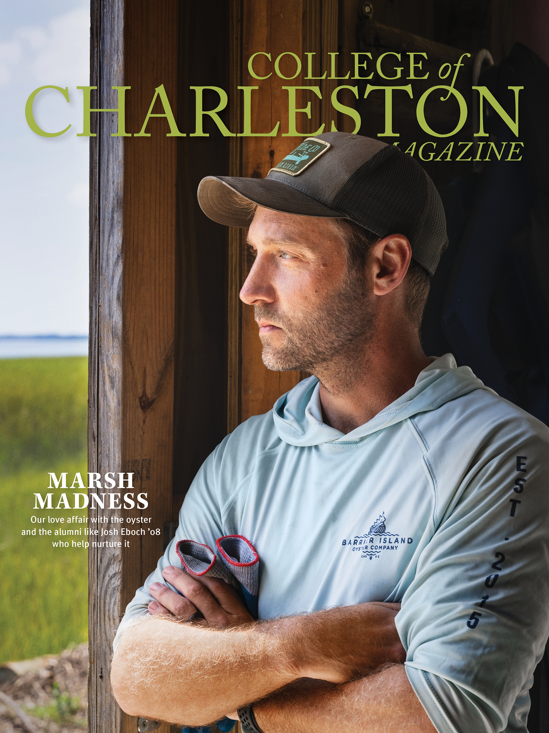 A man in a gray hoodie and baseball cap standing against a wooden post with arms crossed, holding sunglasses, with a green field and title text on the image.