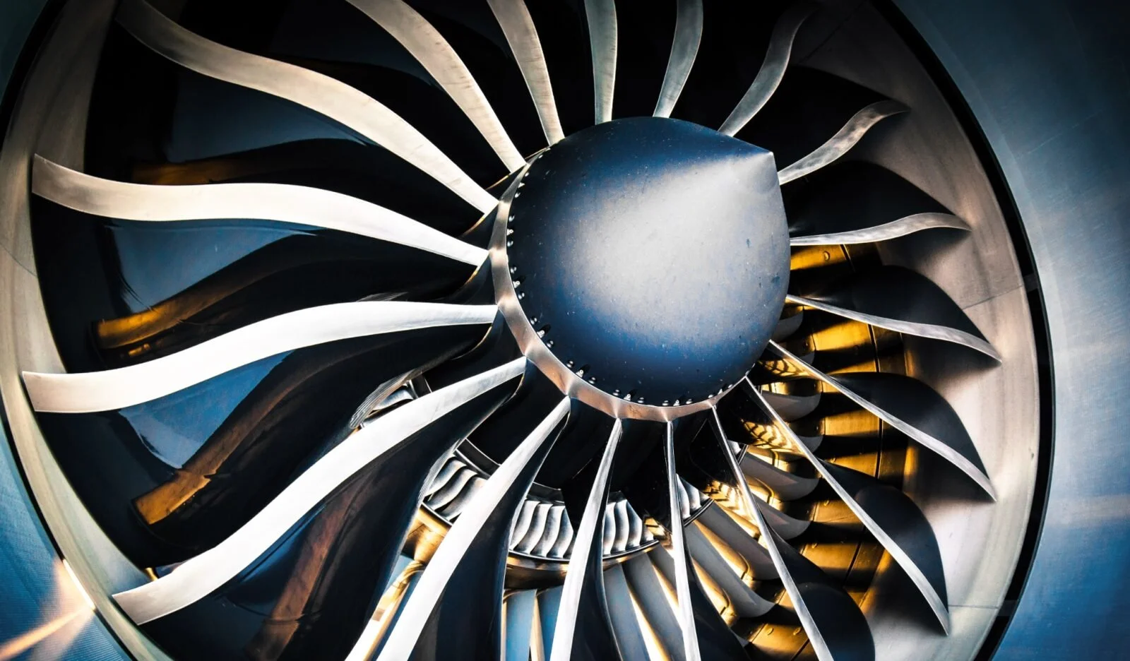 Close-up of a jet engine turbine with blades radiating from the central hub, showing metallic surfaces and intricate design.