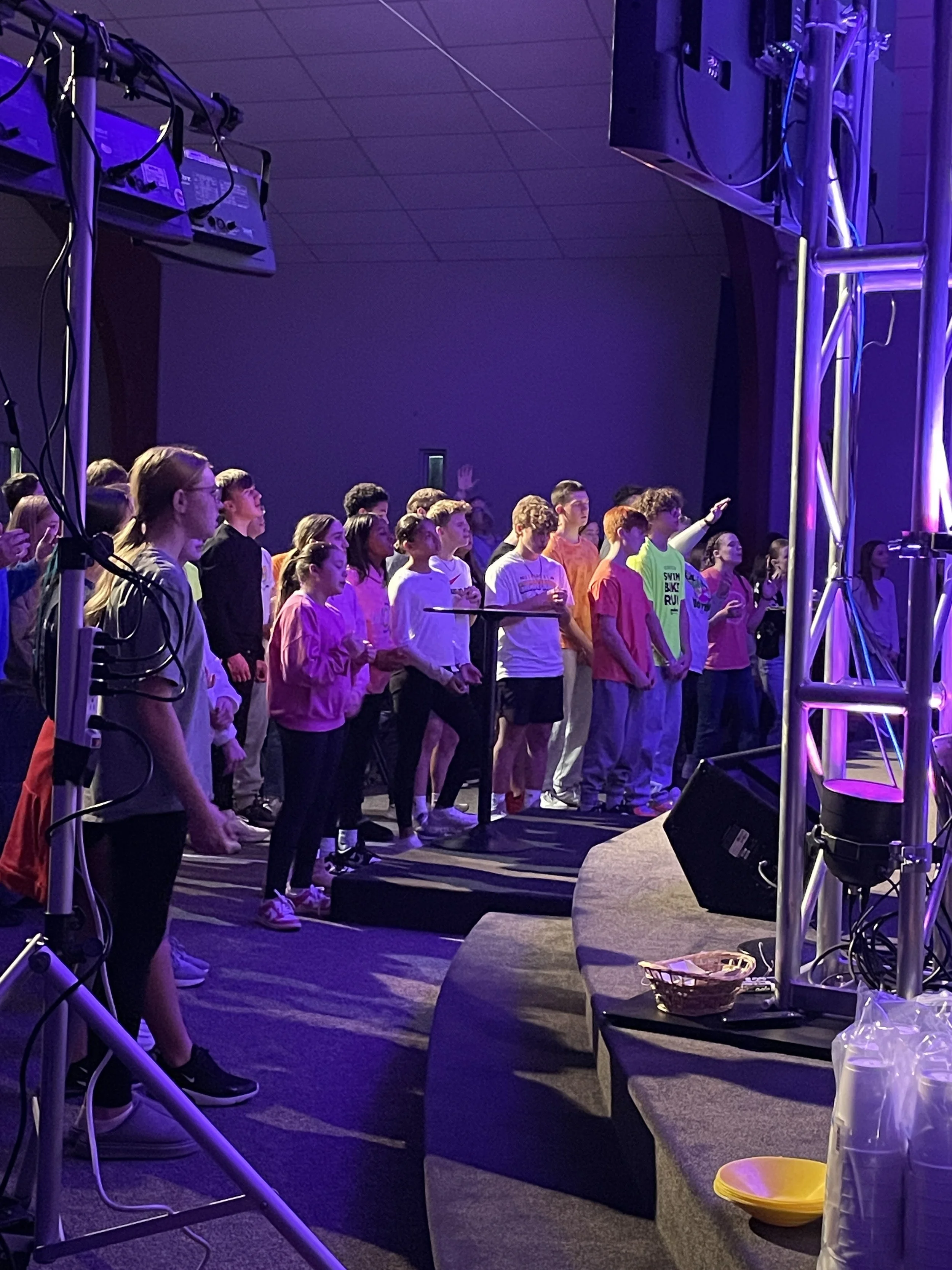 Students gathering around the altar to worship and sing songs. Some are raising their hands. 