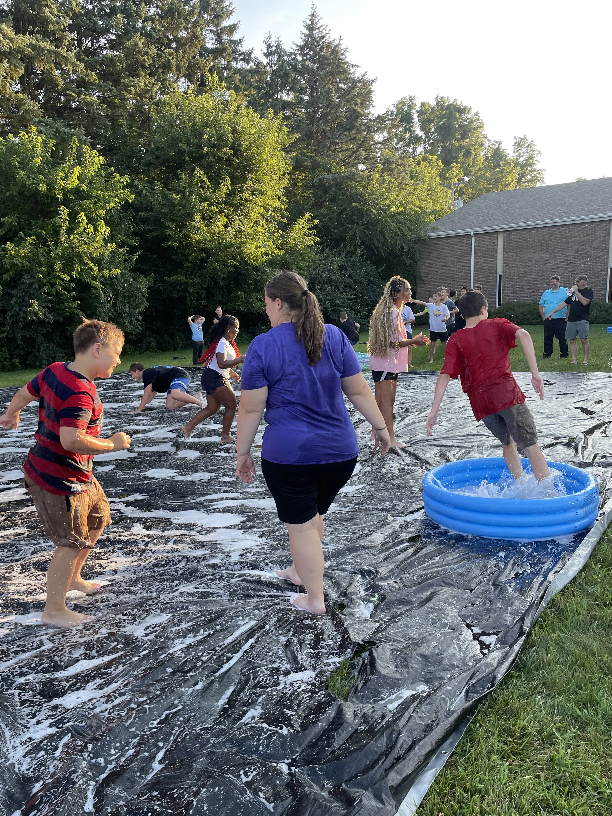 Students and Youth running on a giant slip and slide, playing in water. 