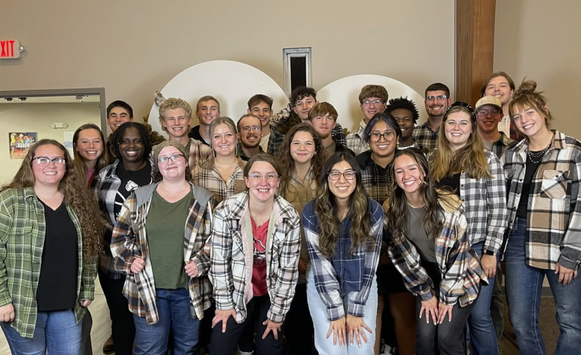 A group of young adults having fun, smiling, and posing for a picture in flannels at the Glad Tidings Church young adults ministry gathering.