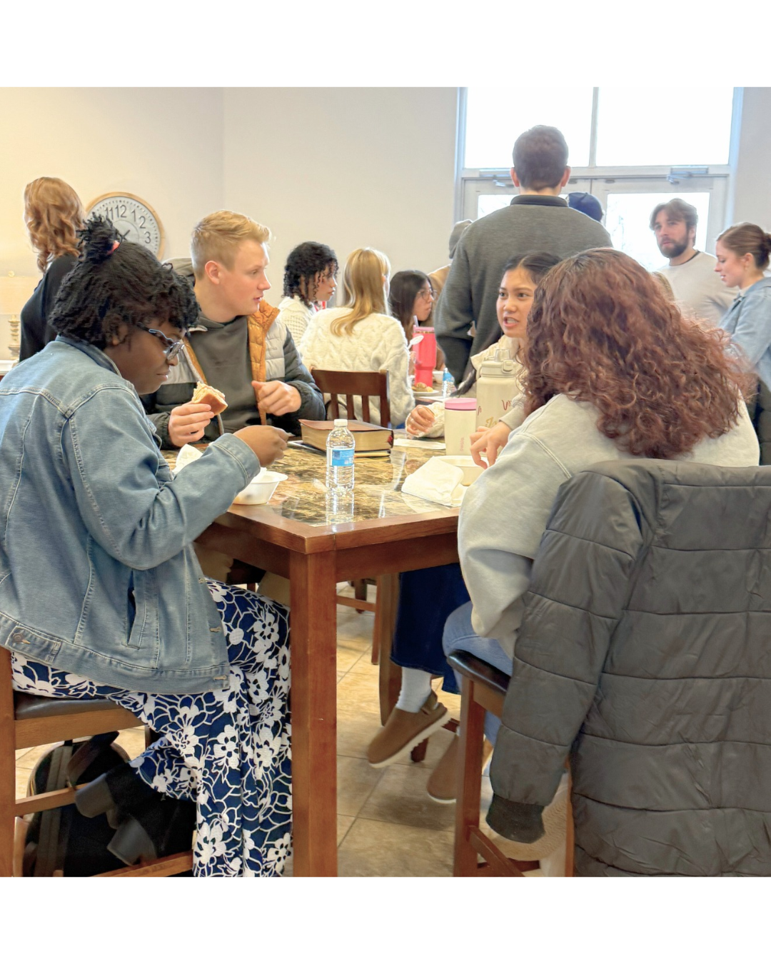 Young adults sitting at tables and enjoying breakfast and conversations at Glad Tidings Church.