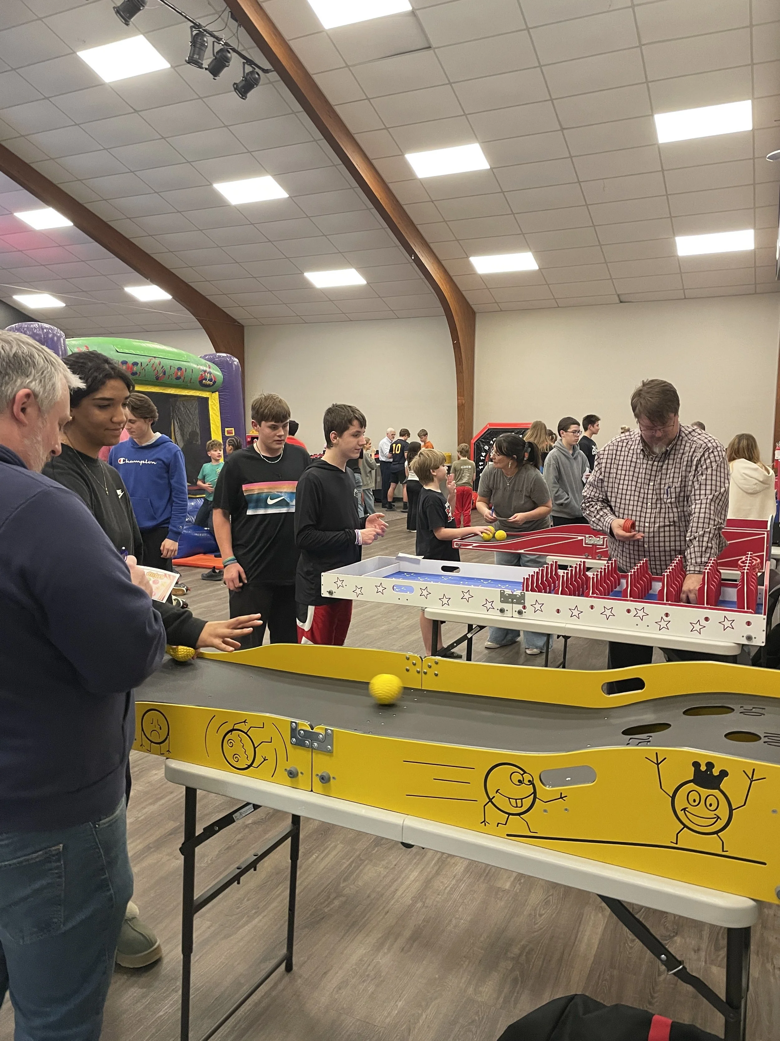 Students and Leaders gather in a room to play carnival games and bounce on inflatables. 