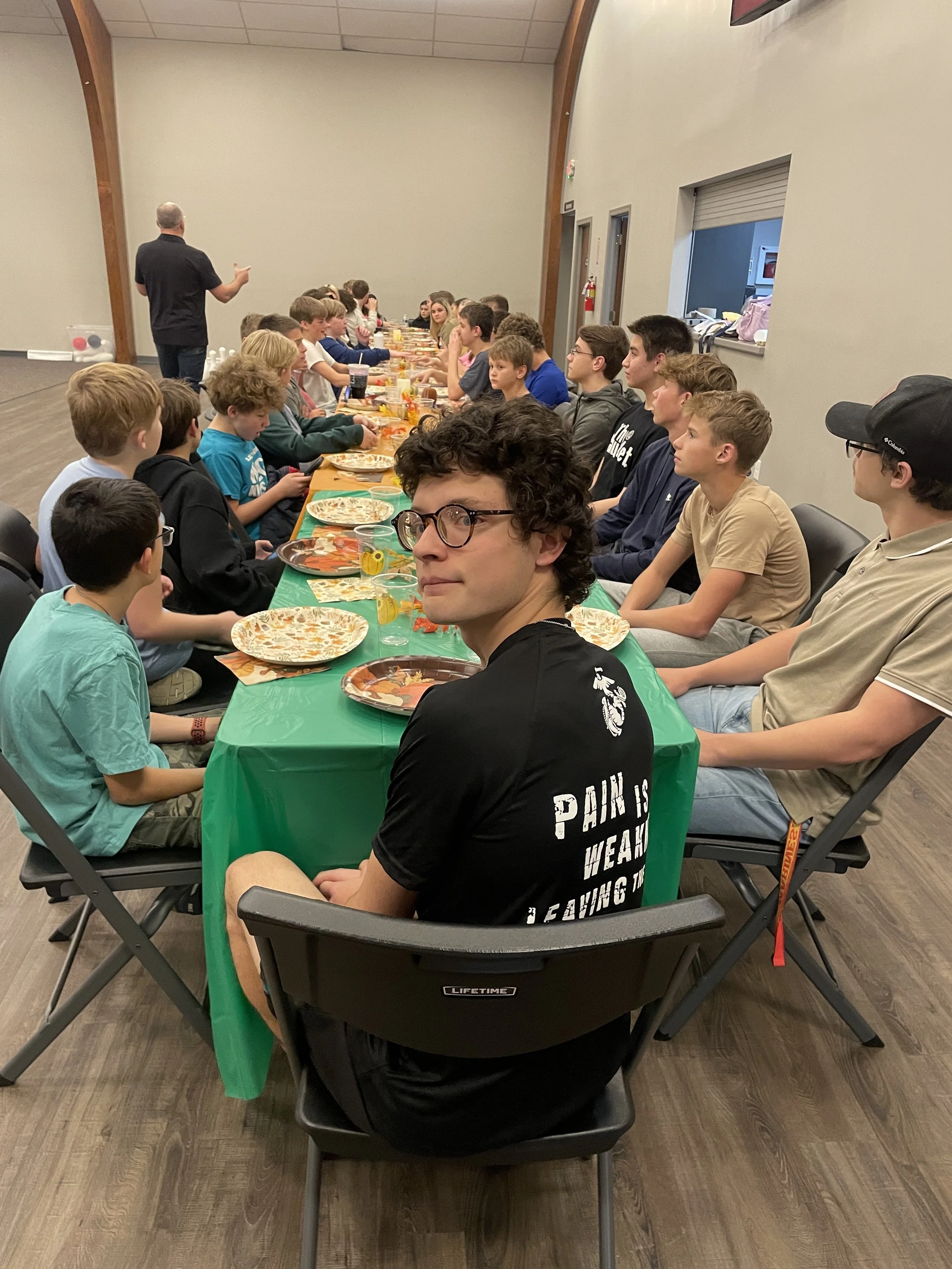 Students and Youth gathered around a Thanksgiving table about to each a meal in community. 