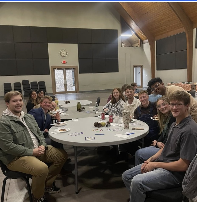 A group of young adults sitting at tables eating at Glad Tidings Church Young Adults ministry friendsgiving event.