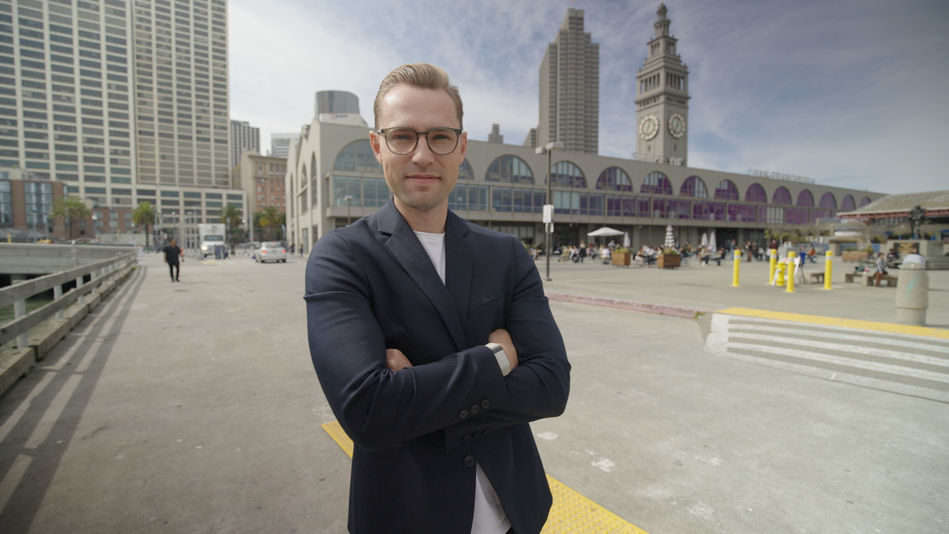 Portrait of entrepreneur Philipp Wehn with arms crossed, standing confidently in front of San Francisco's iconic skyline and Ferry Building.