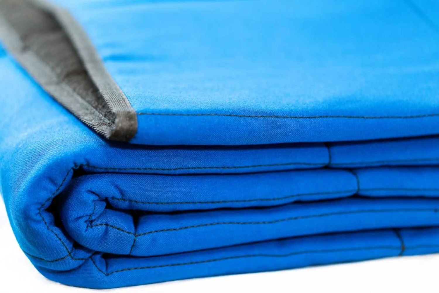 Close-up of a neatly folded blue lithium battery fireproof blanket with gray edging.