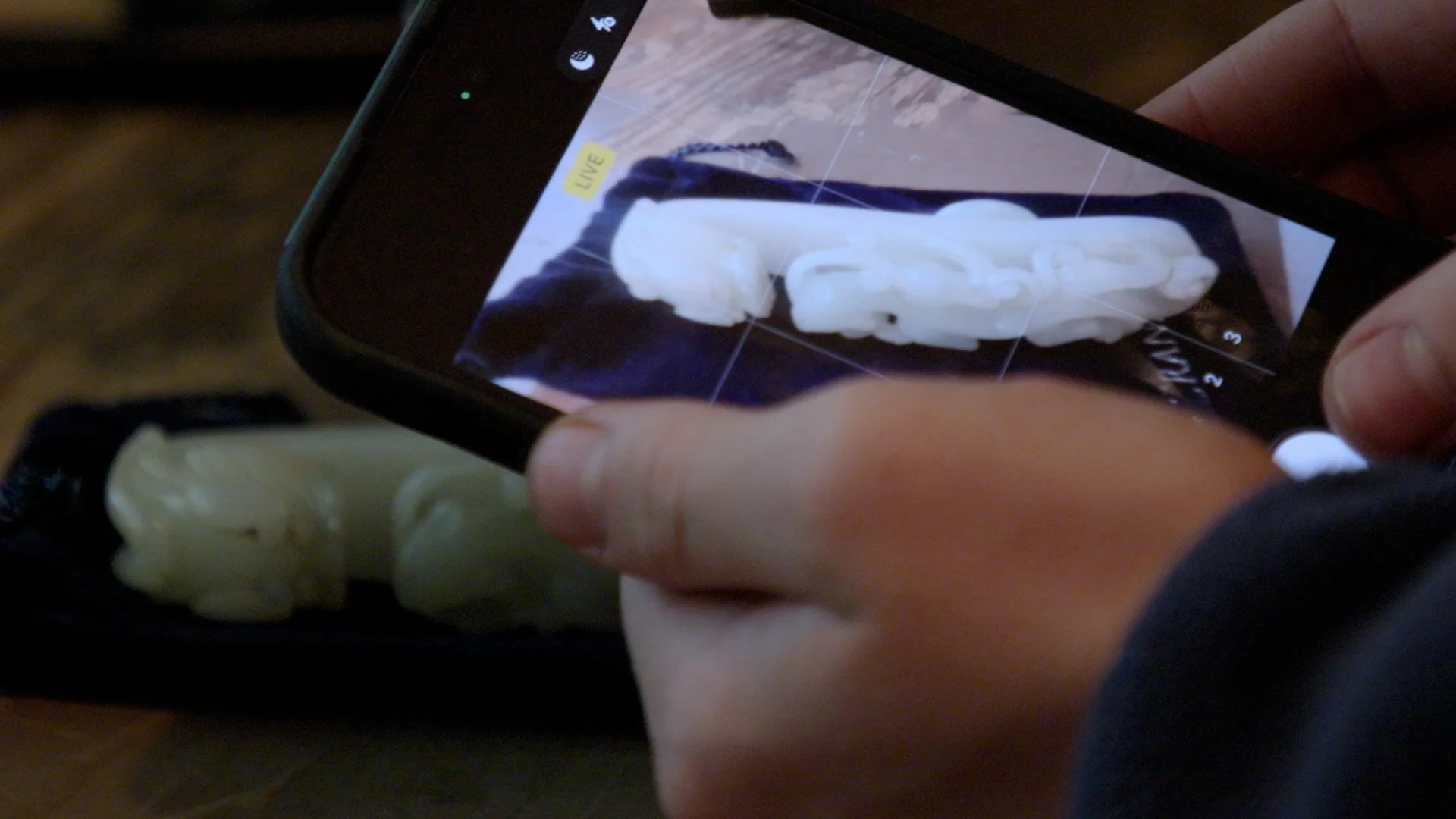 Michael photographs a jade figurine with his phone to price it using Google Lens