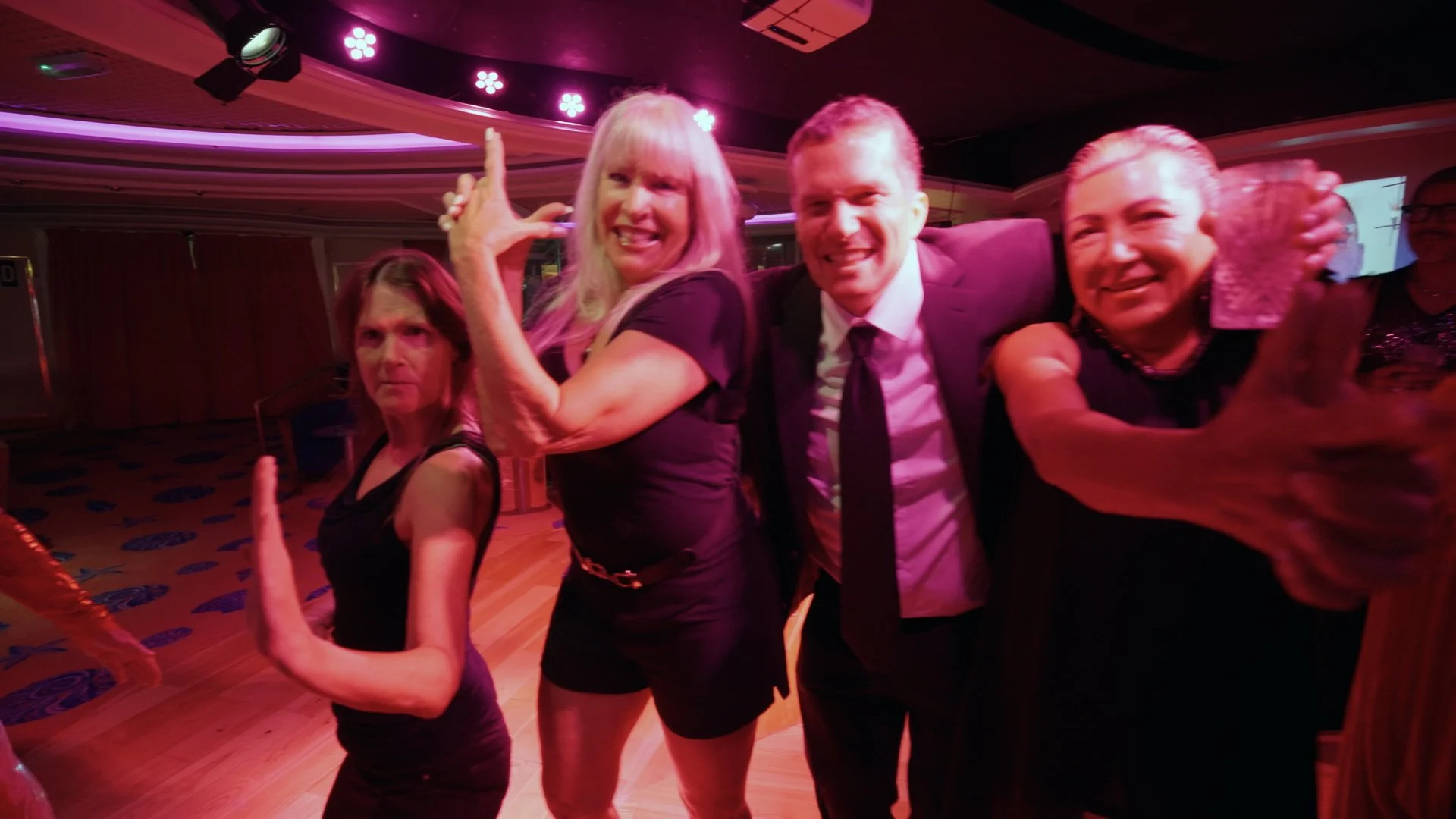 Odyssey residents pose at an evening dance party in the ship lounge under purple lighting