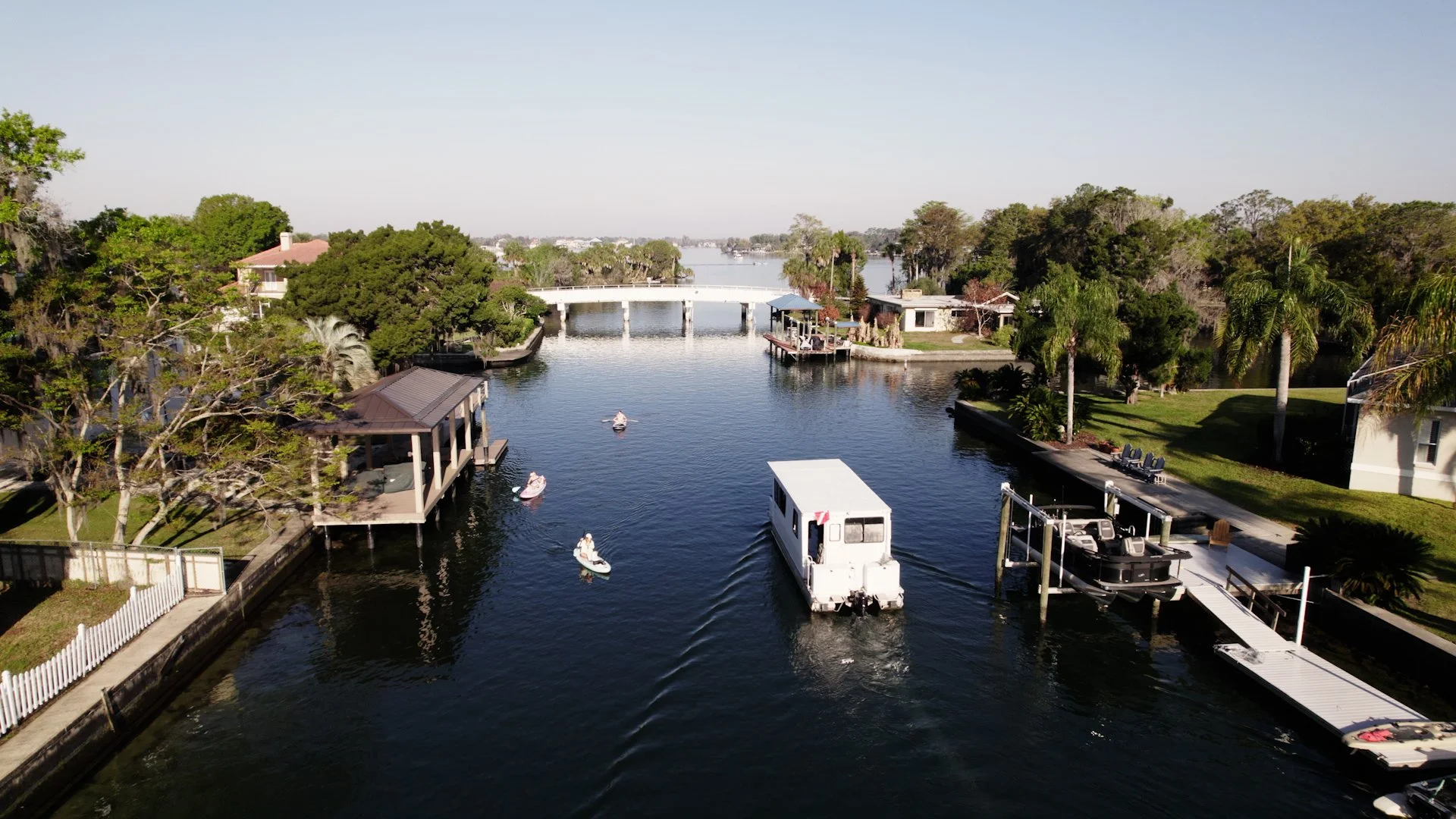 Aerial view of a Crystal River canal with Captain Spann's tour boat, kayakers, and waterfront homes leading toward open water