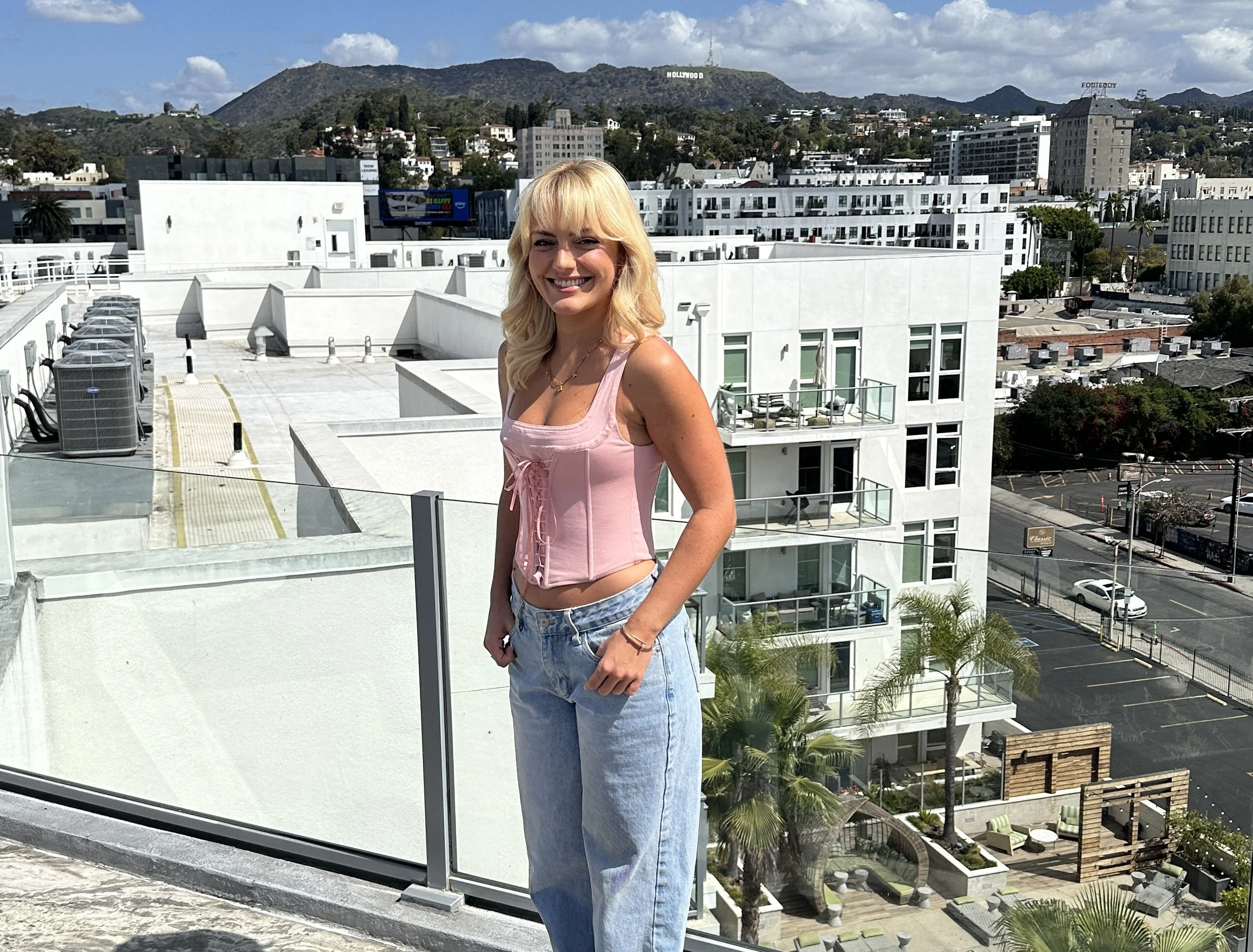 Anuschka van Lent stands on a sunlit Hollywood rooftop with iconic views in the background during a day of filming for our documentary. Discover her journey from Germany to LA.