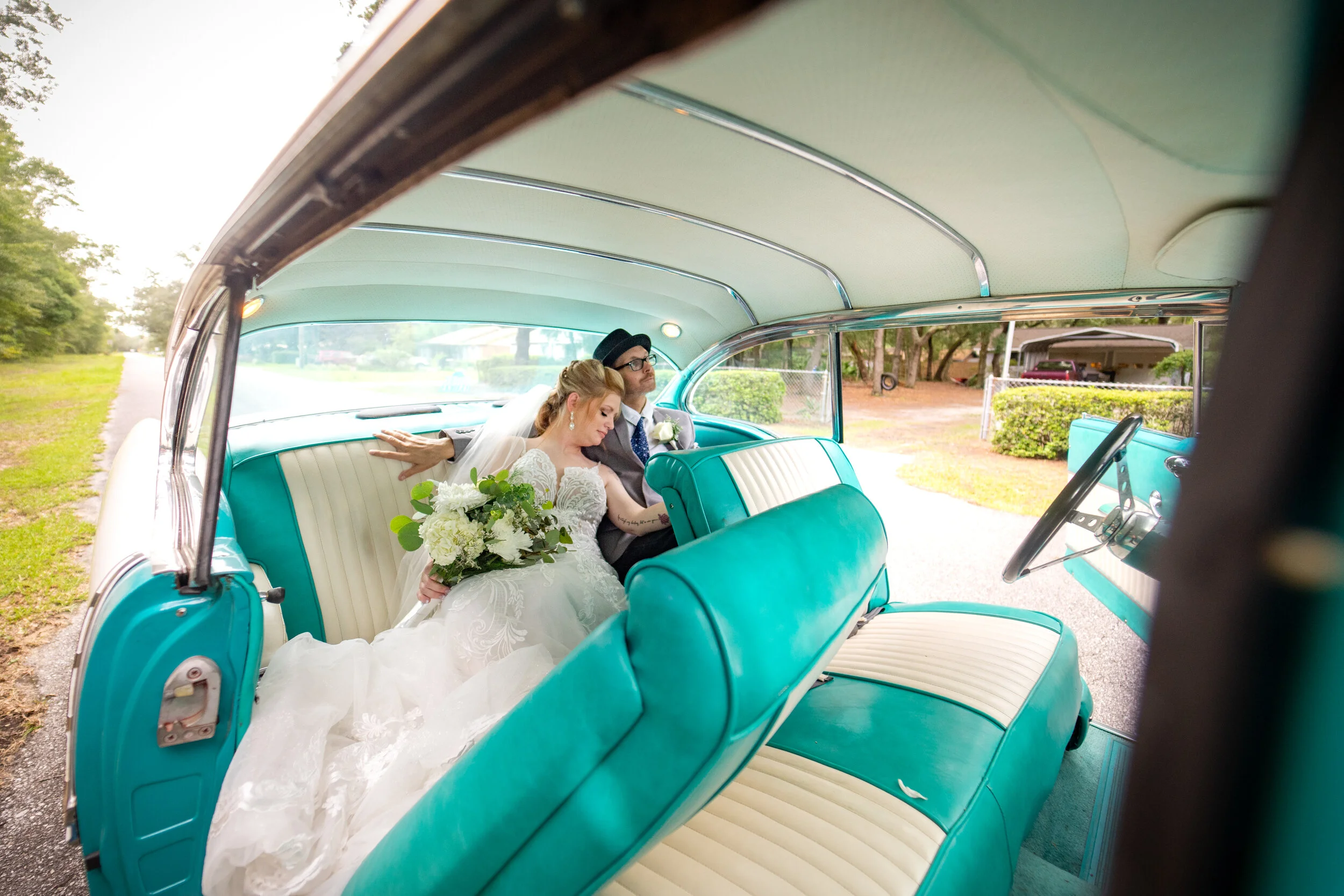 A bride and groom sitting inside a vintage turquoise car, celebrating their wedding. Pensacola wedding photography - pensacola wedding photographer