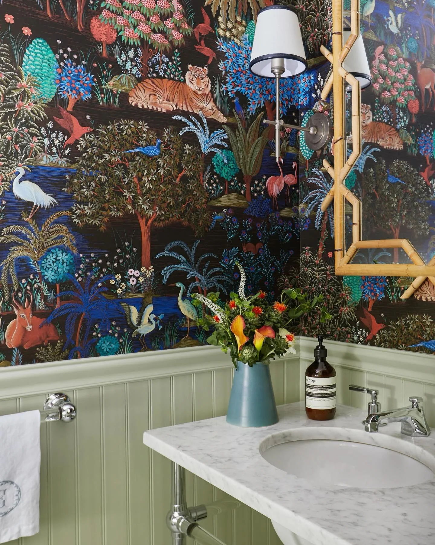 Let&rsquo;s break down this jungle inspired powder room: Pierre Frey Le Jardin Du Palais wallpaper | sage beadboard wainscoting | Carrara marble console sink | bamboo fretwork mirror | @aesop on the counter because of course! Save this for your next 