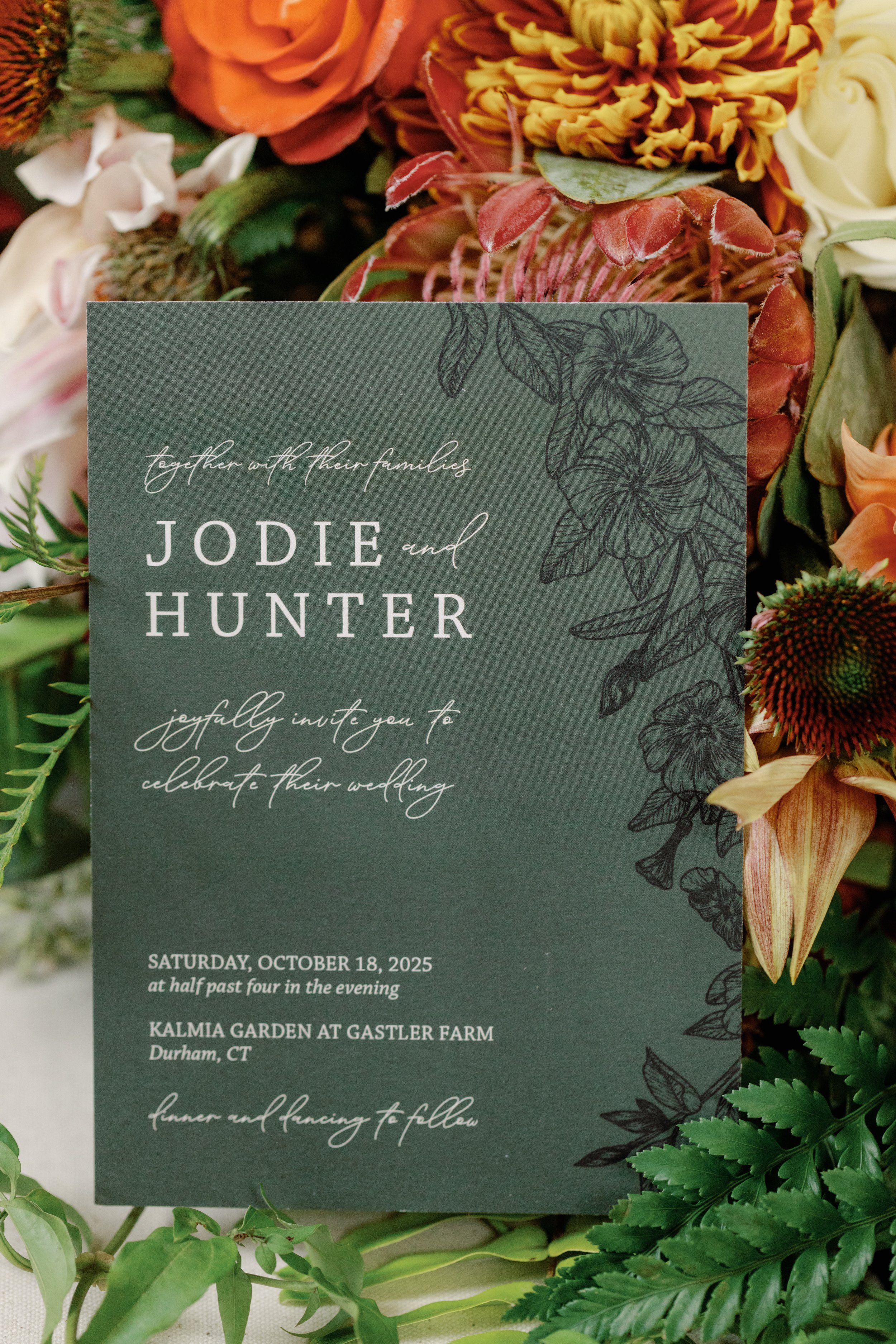 Forest green wedding invitation for Jodie and Hunter with cream lettering and botanical line art, surrounded by rust and marigold autumn florals. Custom wedding stationery by Studio Pierson.