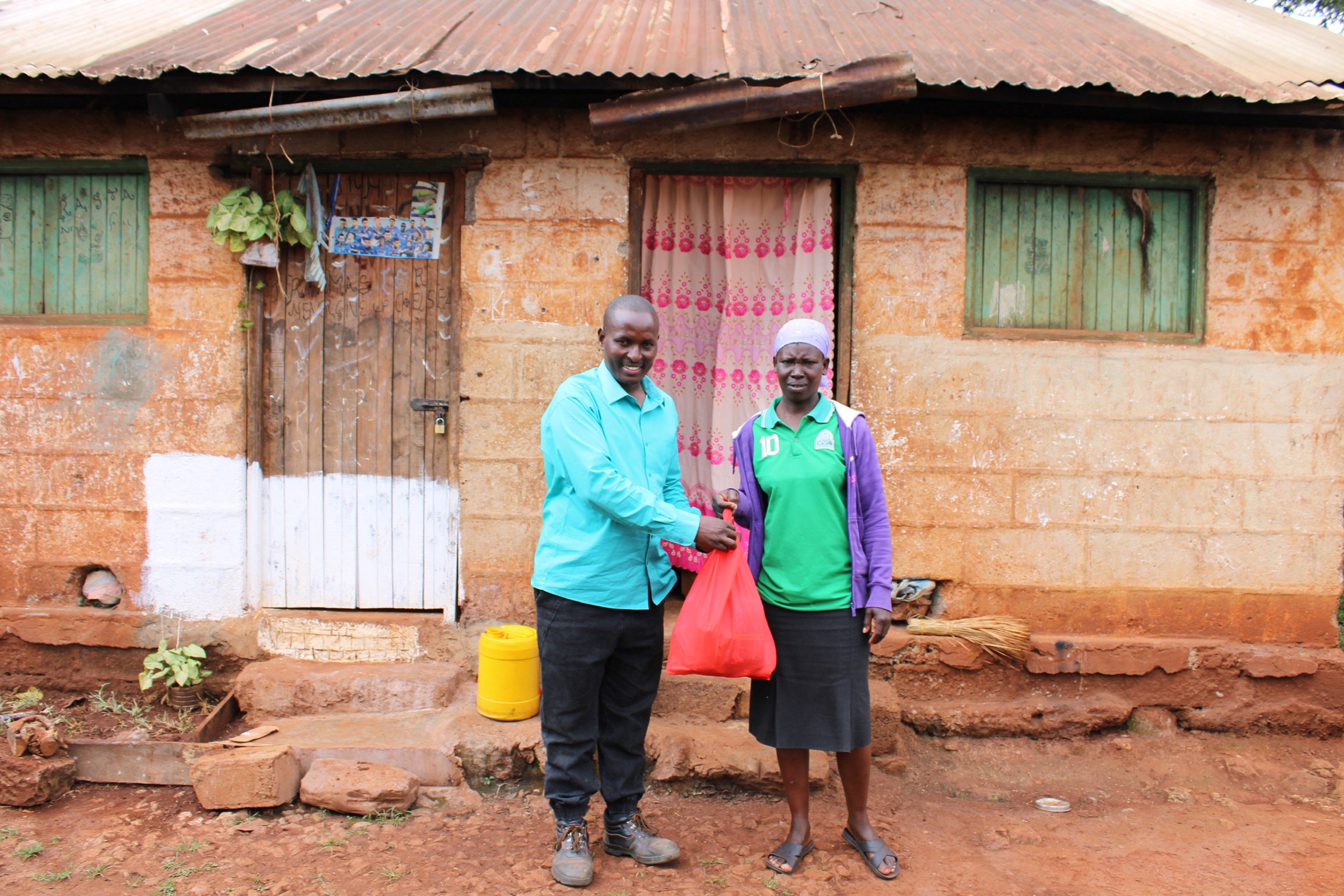 Pastor Robert presents food package to a monthly recipient.