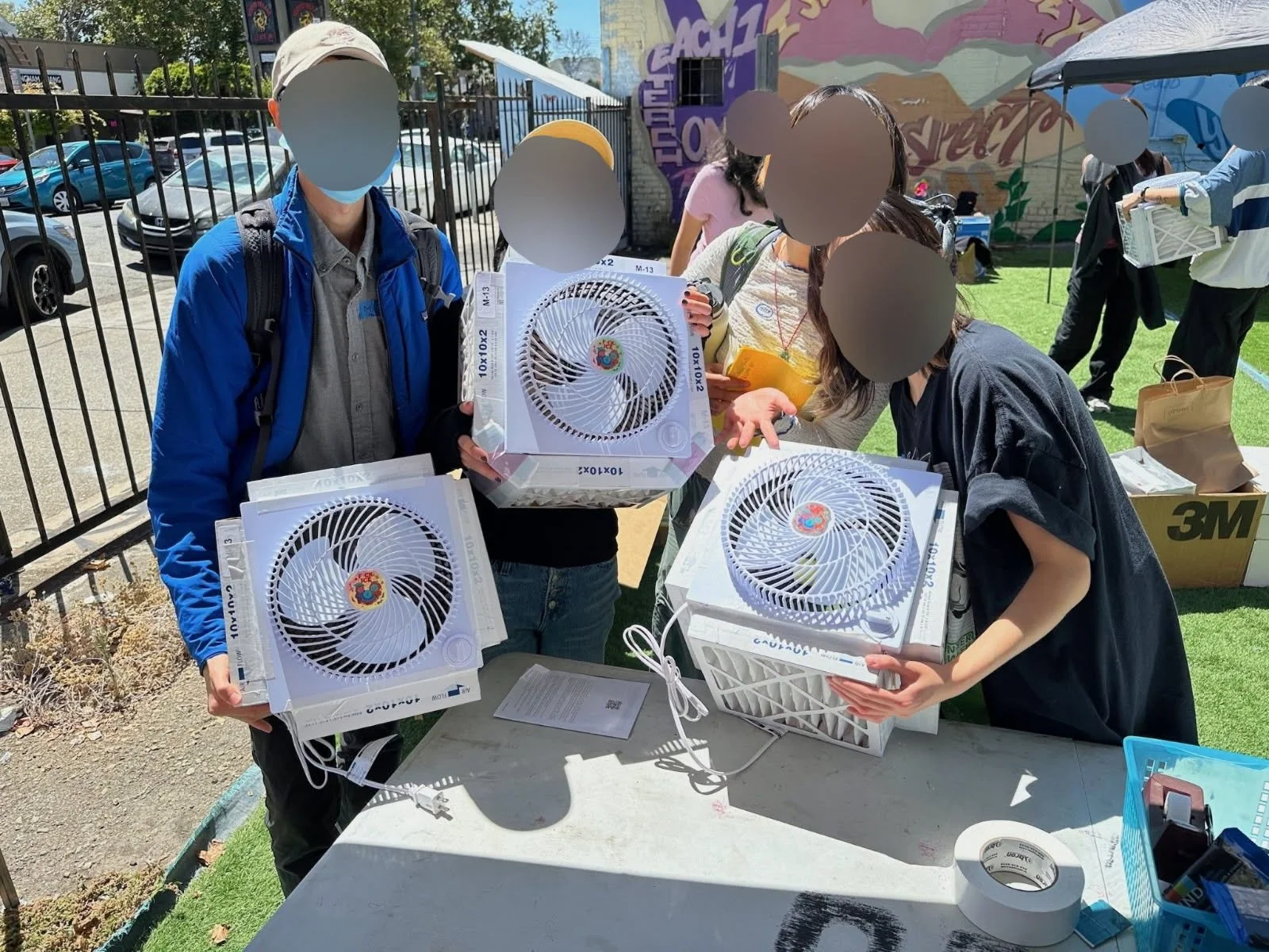 There are four people holding three mini CR boxes with "Fuck ICE" stickers in the center of each fan (from LavNix's Drop the MIC event).