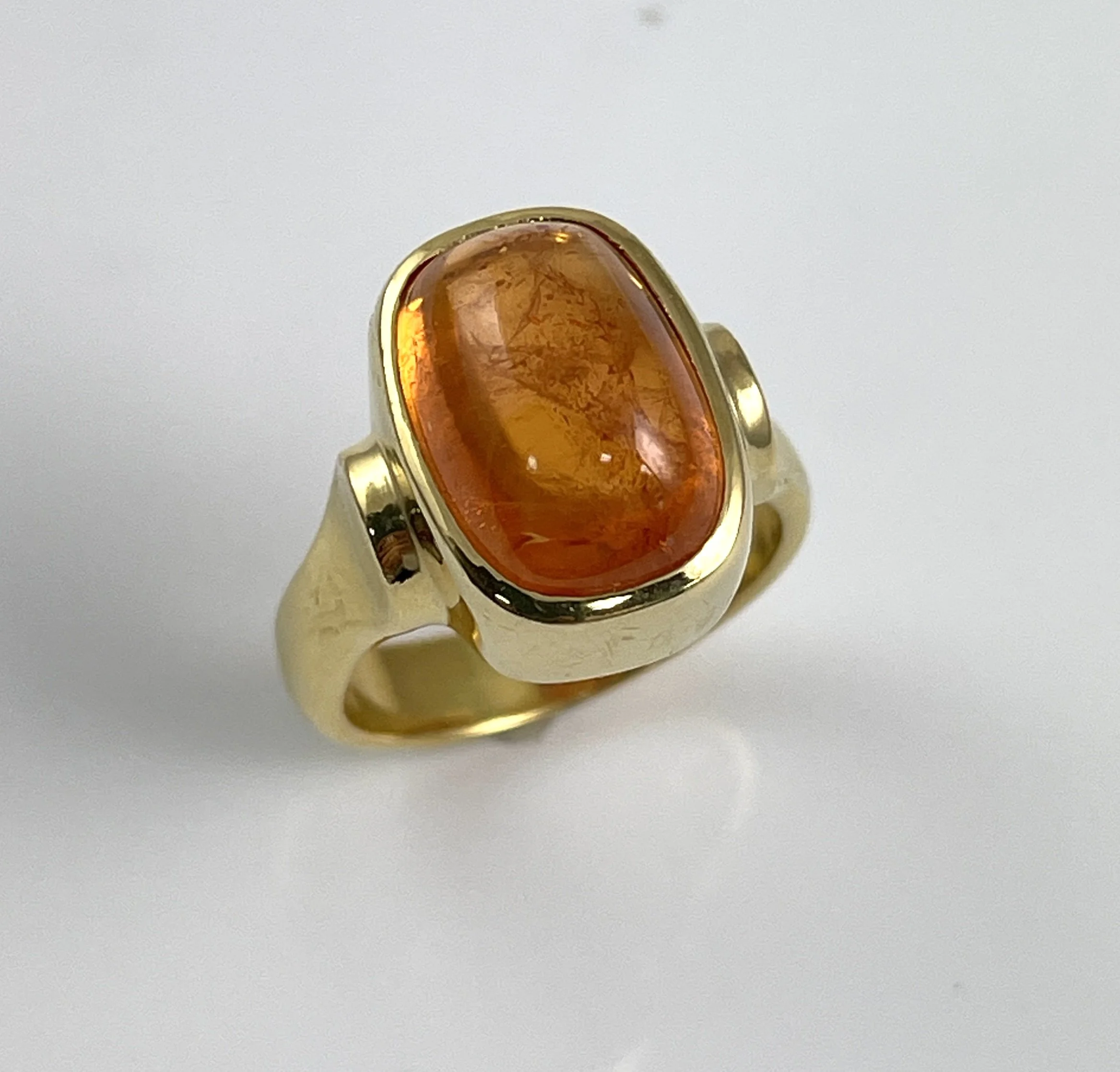 18K ring set with a 10.95ct Mandarin Garnet cabochon.  One of a kind.