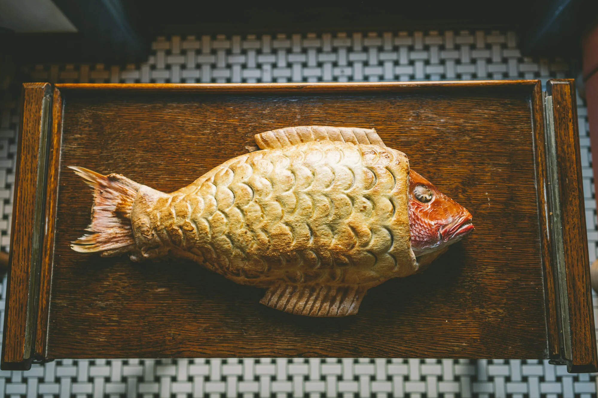 Snapper prepared with salt crust on a brown table.