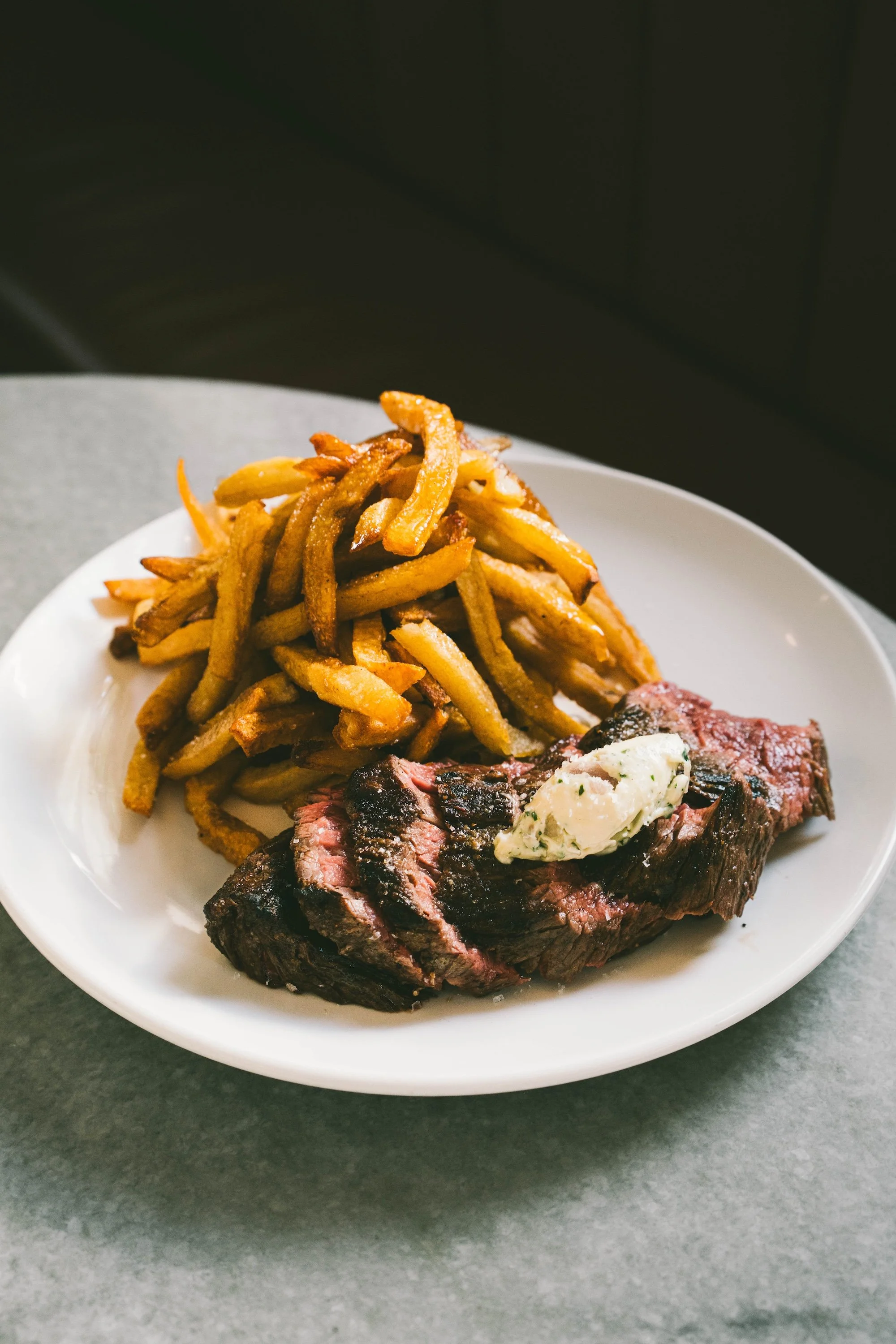 Steak frites cook with maitre d butter and duck fat french fries on a plate.