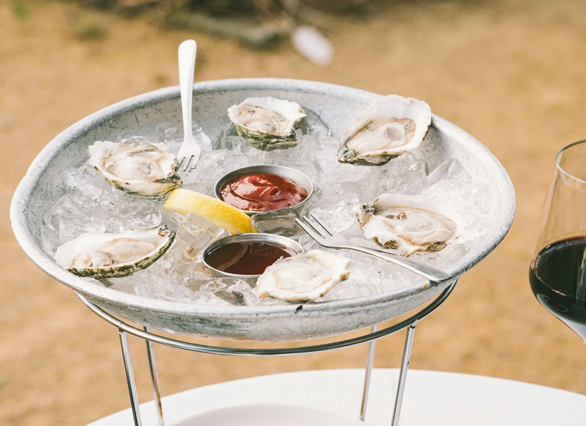 Raw shucked oysters in ice and on a tray in an outdoor courtyard.