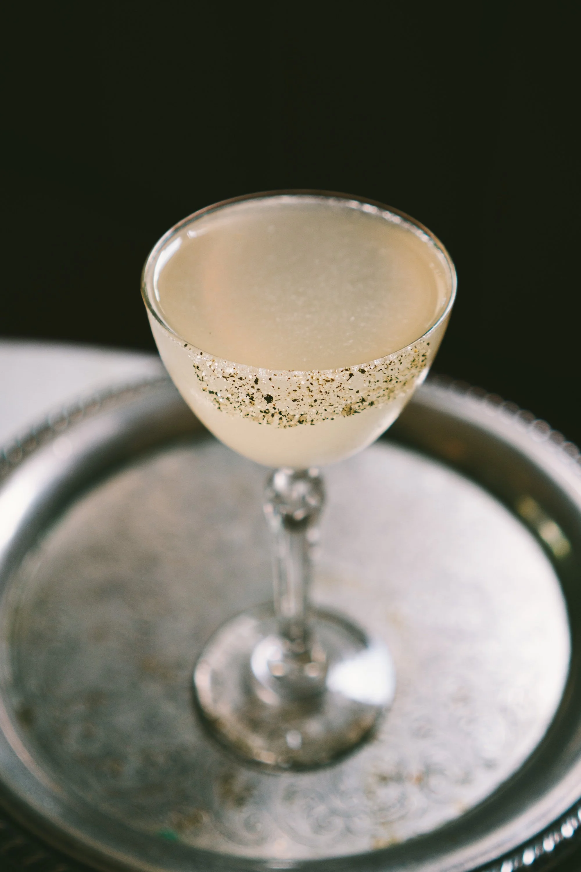 Seasonal cocktail in a vintage glass on a silver tray.