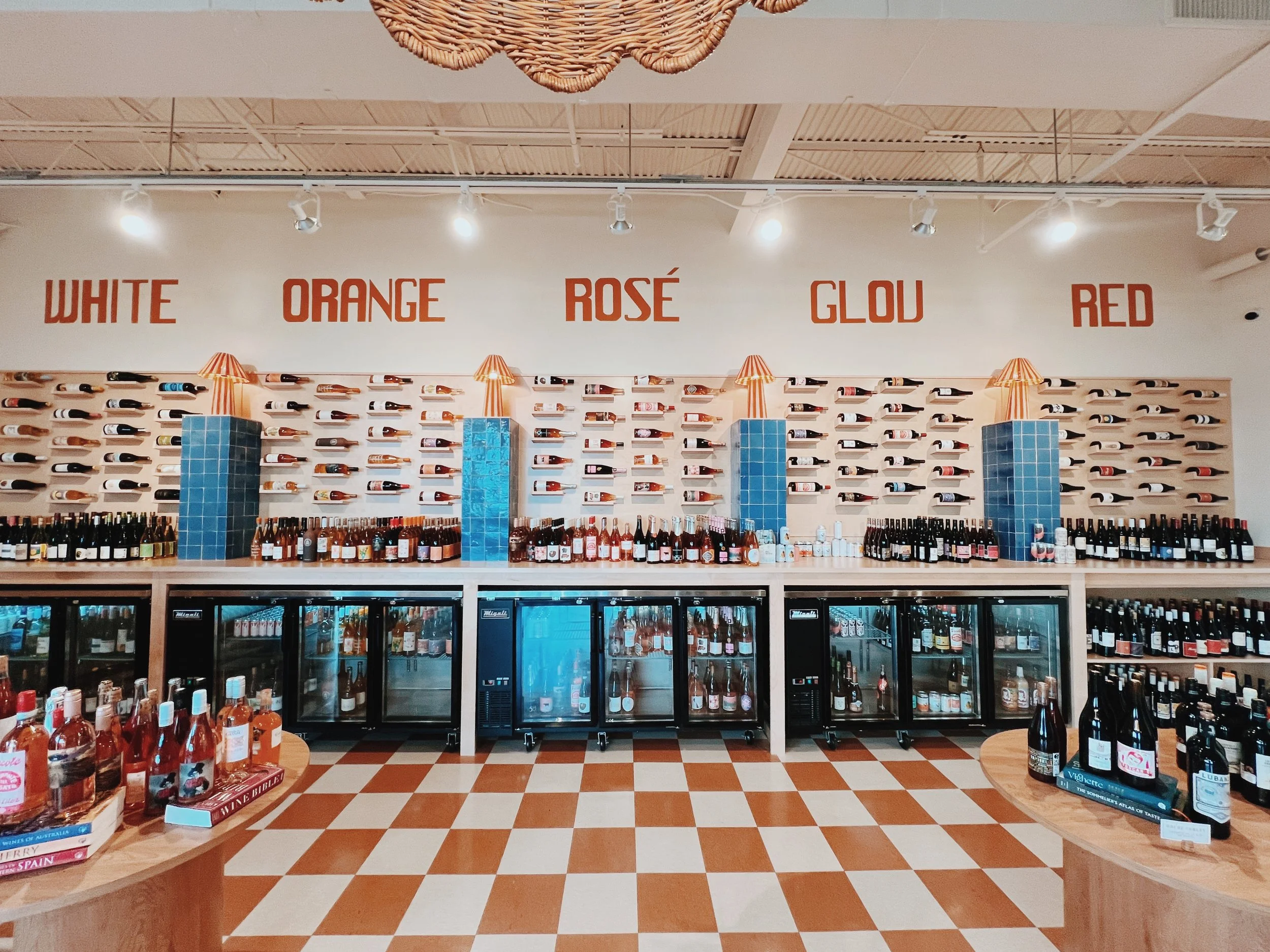 photo of many wine bottles on the wall and in coolers.