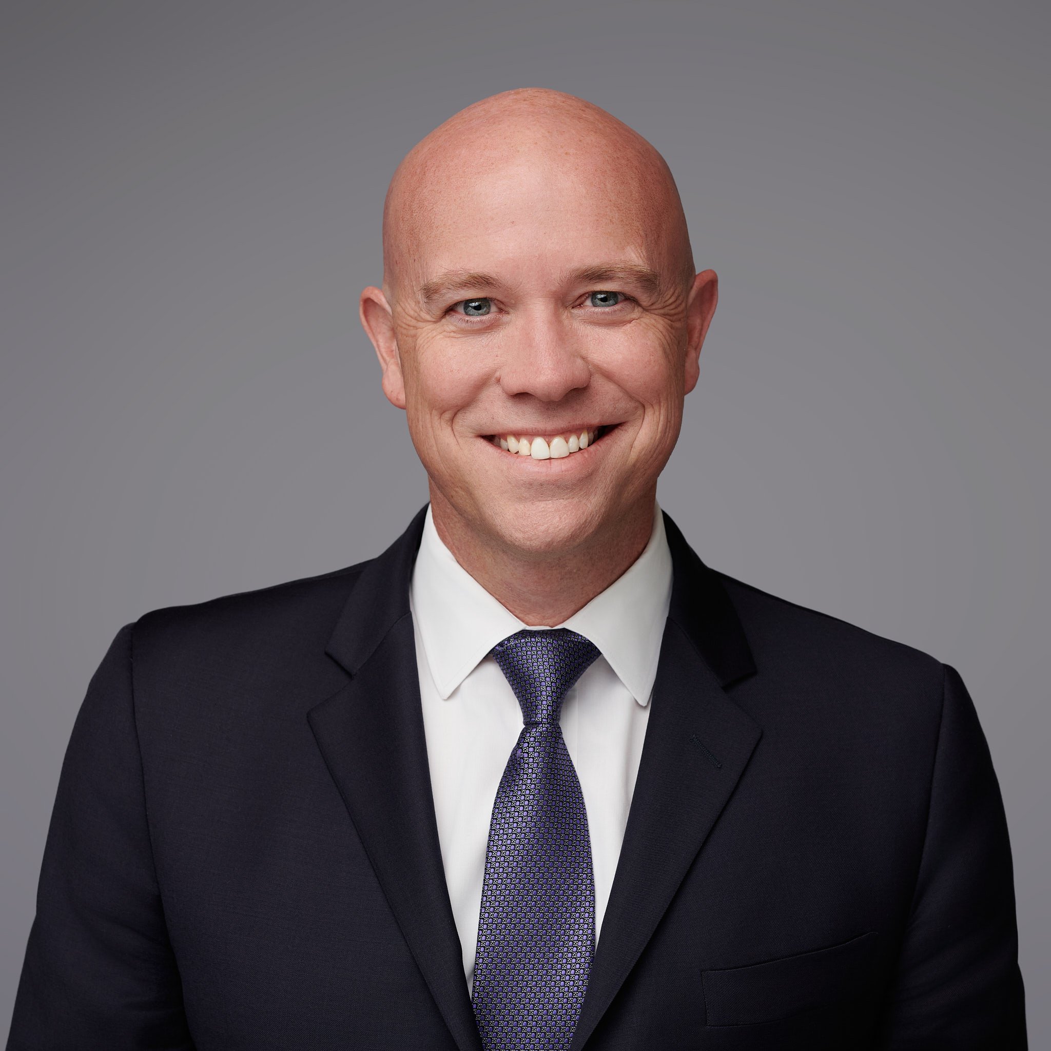 Approachable business headshot of a financial portfolio manager on a classic gray studio background in Stamford CT.