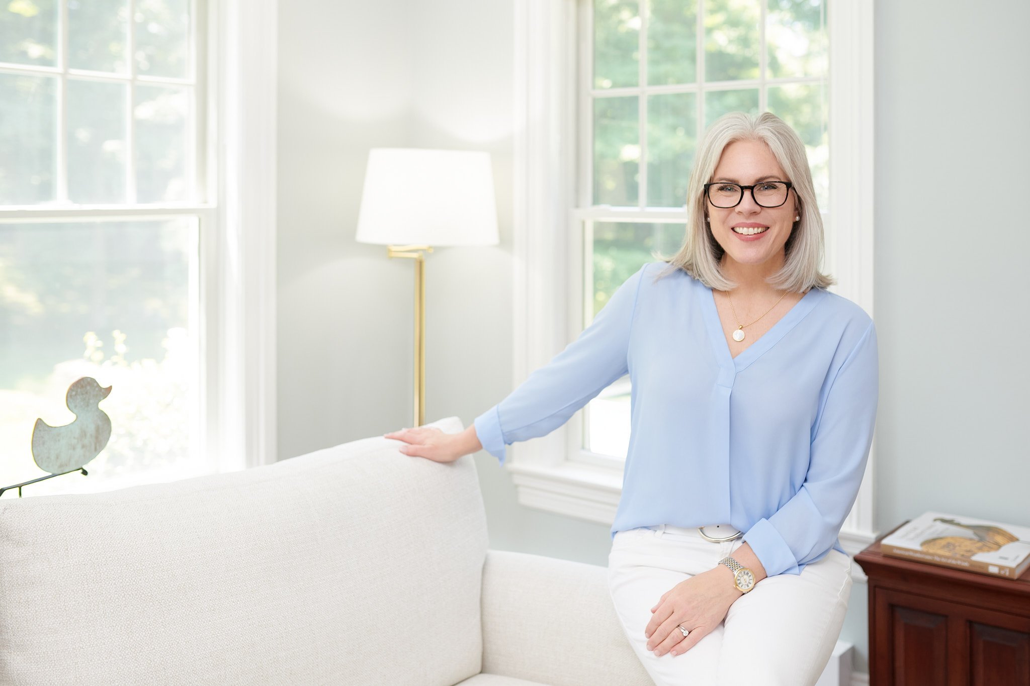 Approachable lifestyle portrait of Mallory Blake sitting in a bright sunlit room, captured by N. Lalor Photography, a professional Westport-based brand photographer.