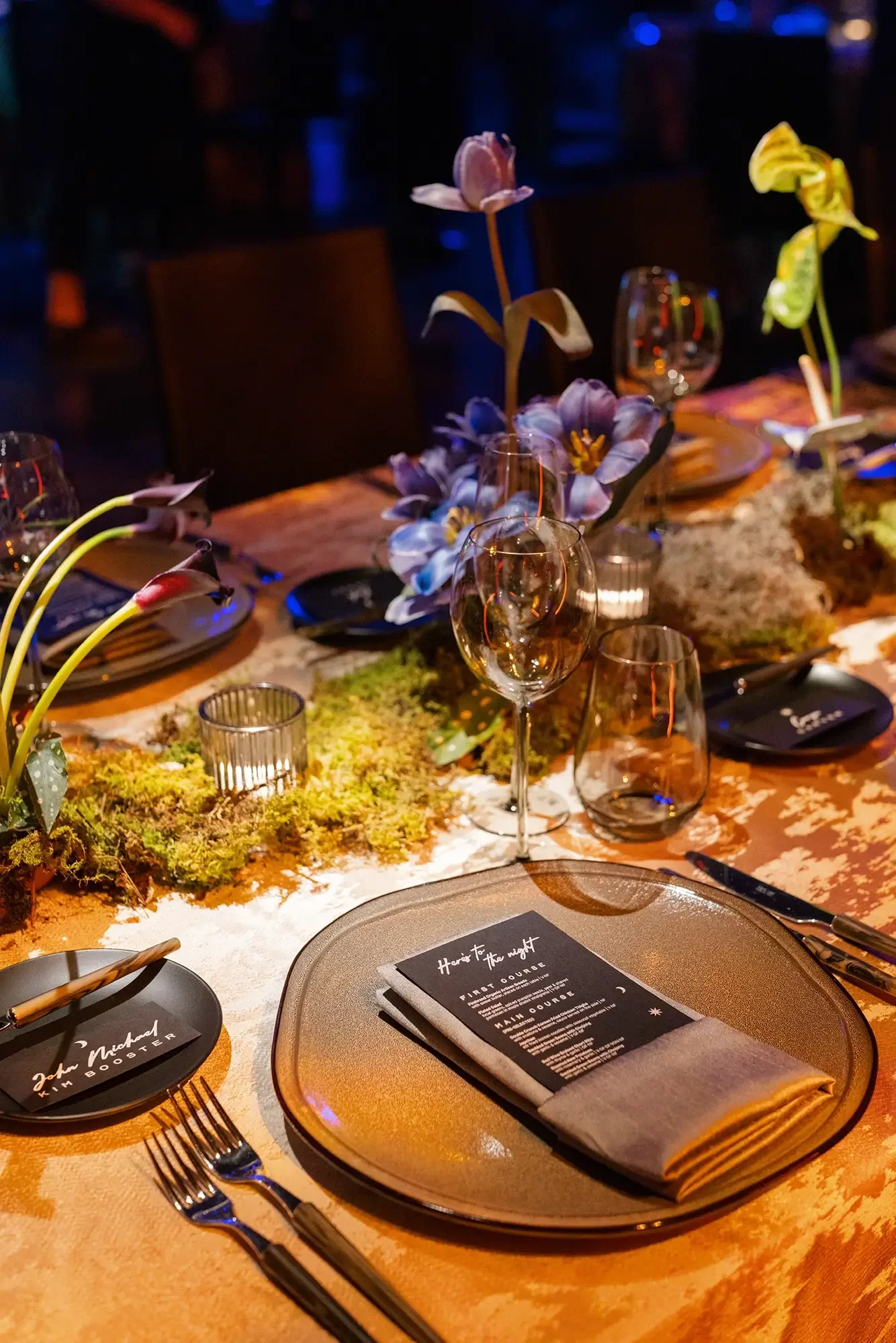 An elegant wedding dining table decorated with flowers, candles, glassware, and a menu, set for a wedding reception