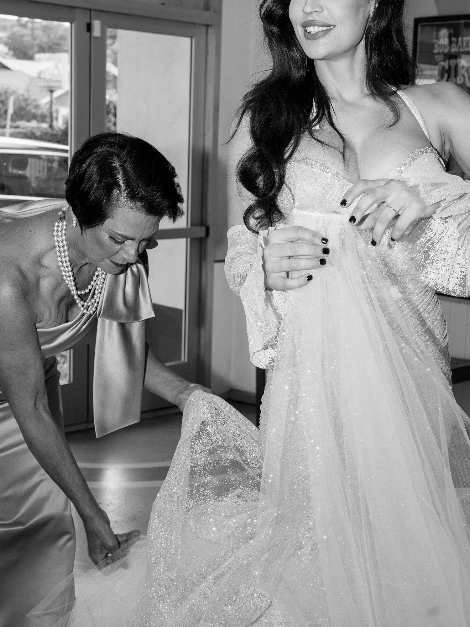 A woman in a wedding dress receiving assistance from her mother before the ceremony.