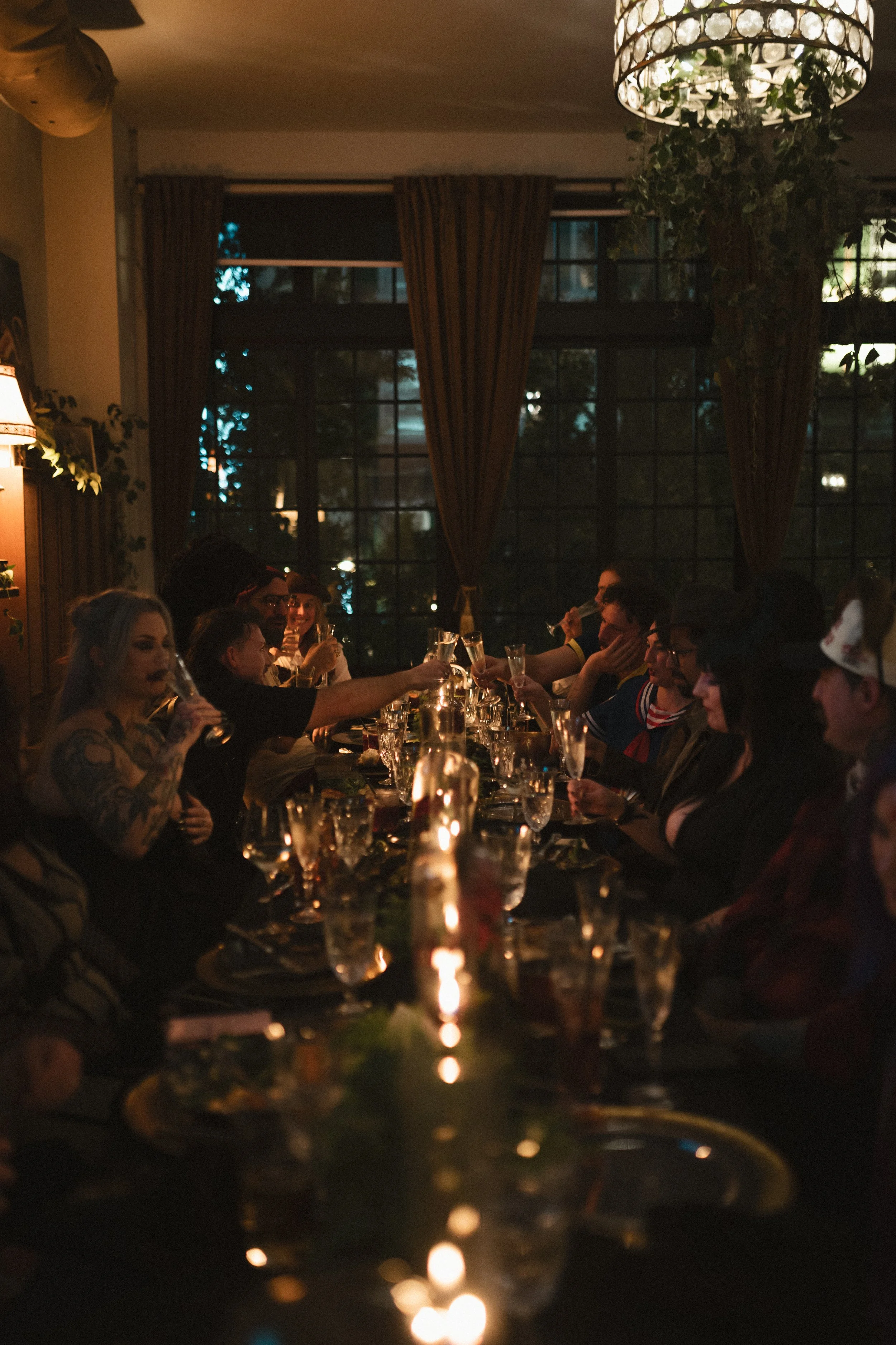 Guests dining and raising champagne glasses at a candlelit restaurant dinner party