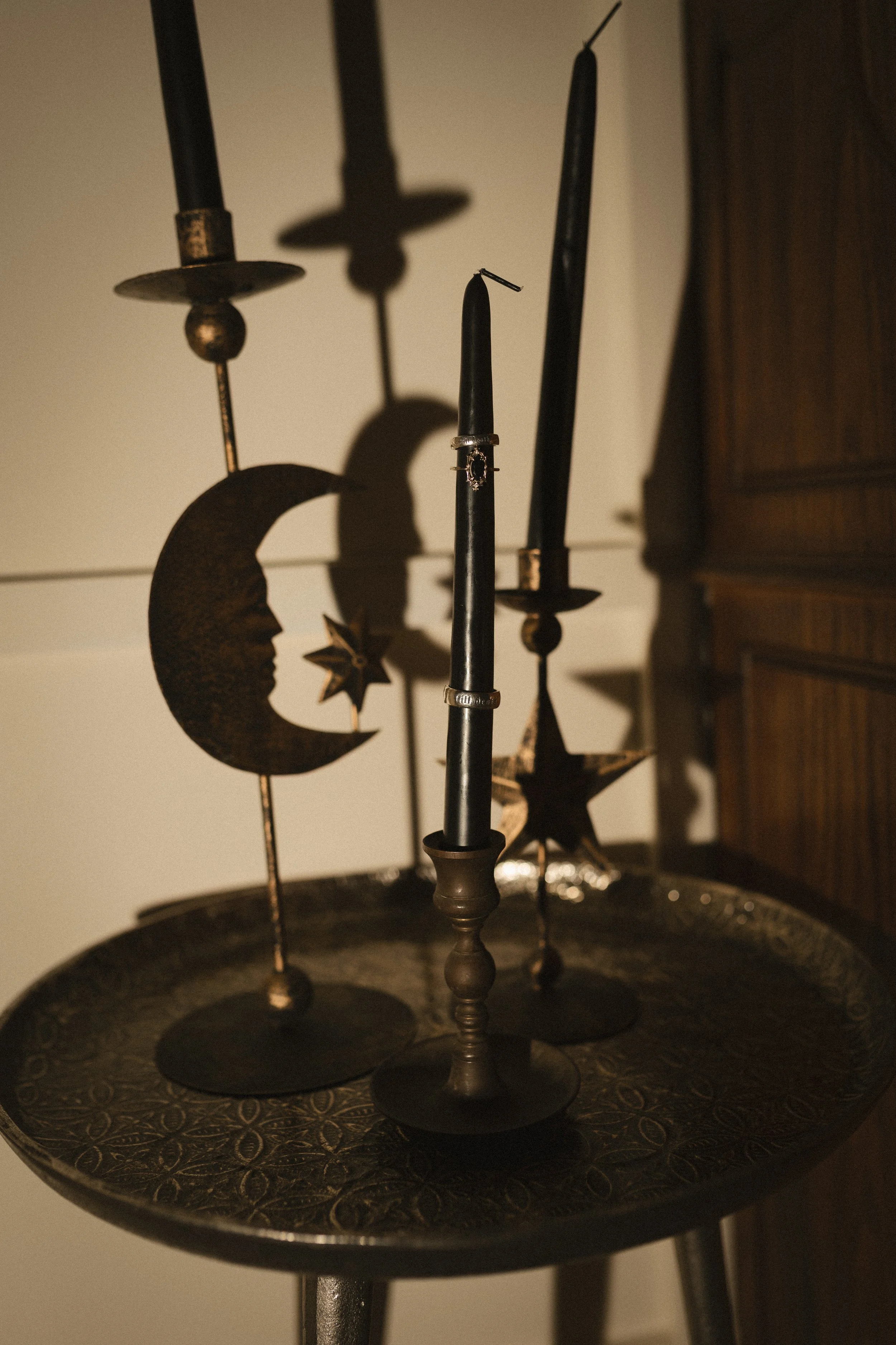 Vintage black candlesticks casting dramatic shadows on an ornate round table.