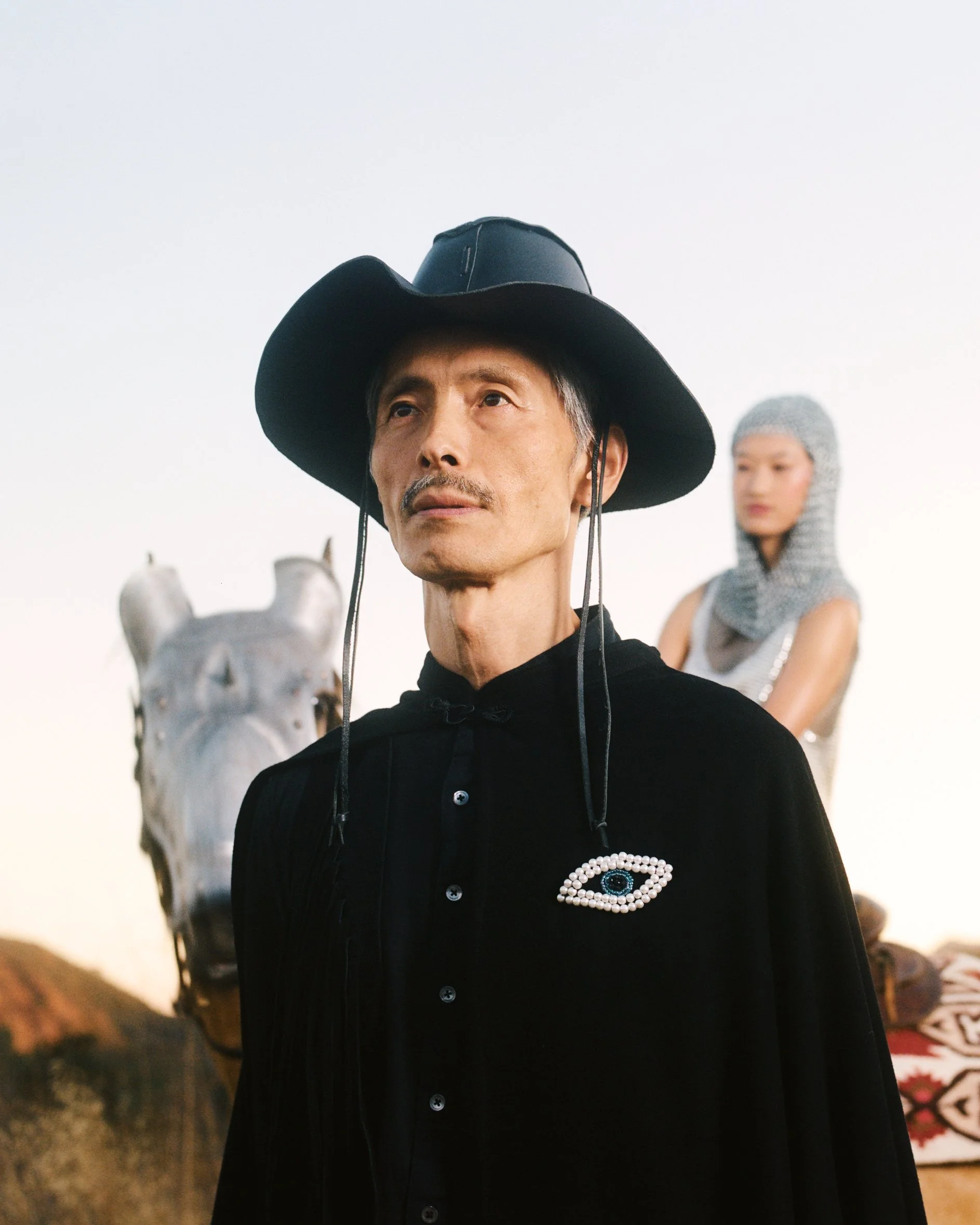Drawing on the delusional journey of Don Quixote, and borrowing from surrealist painters like René Magritte and Jane Gaverol, a man is depicted at the twilight of his immigrant journey as he sits on a chair, flanked by a younger woman, who’s about to