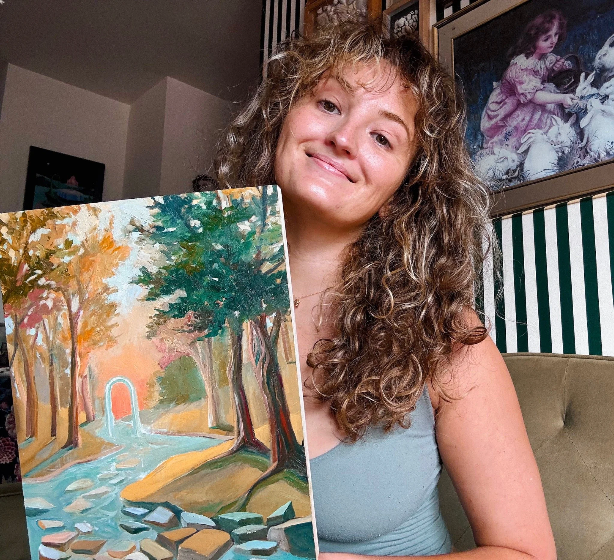 Artist Sarah Delli Colli holding an original colorful landscape painting.