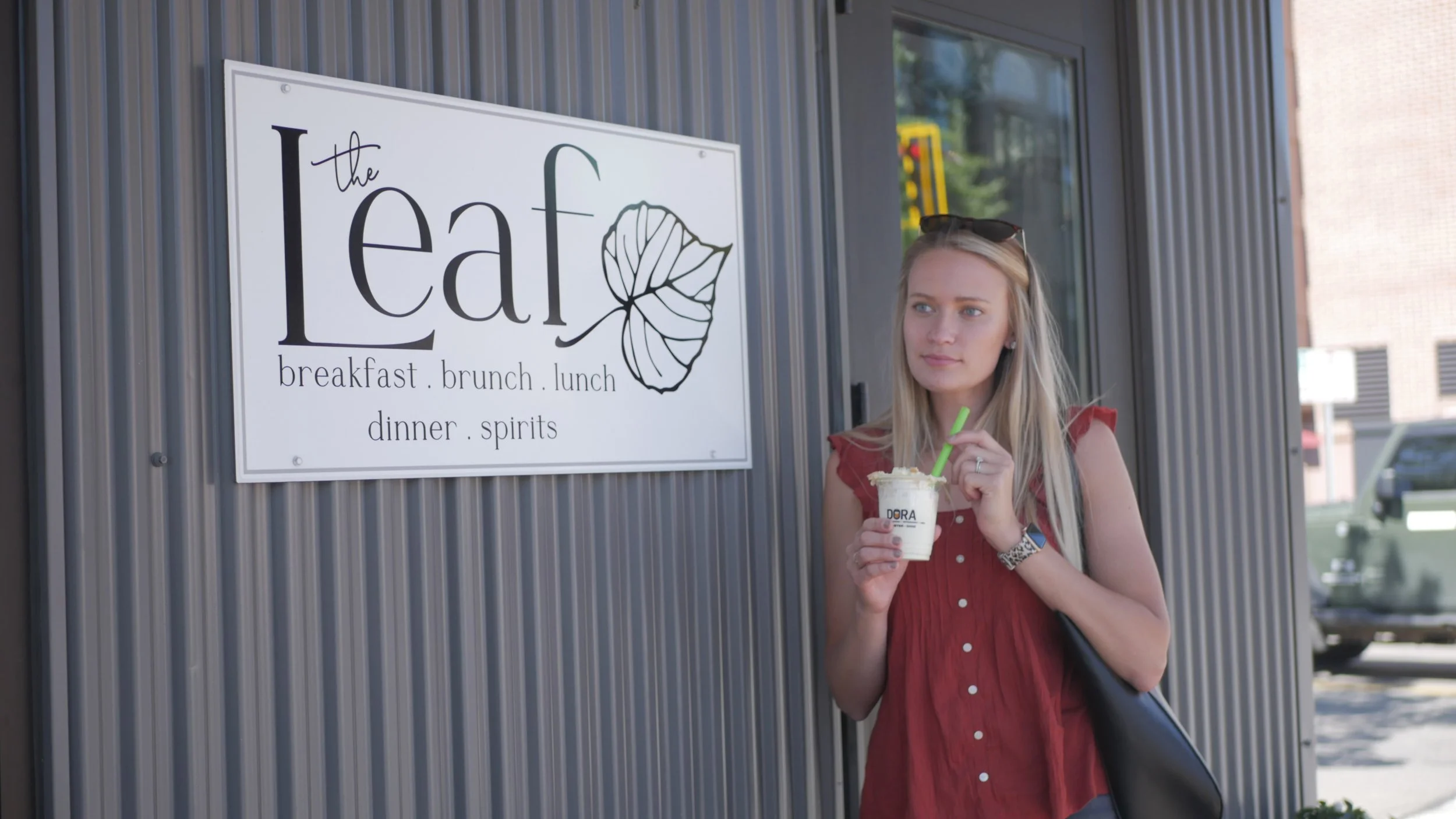 Woman standing in front of The Leaf sign