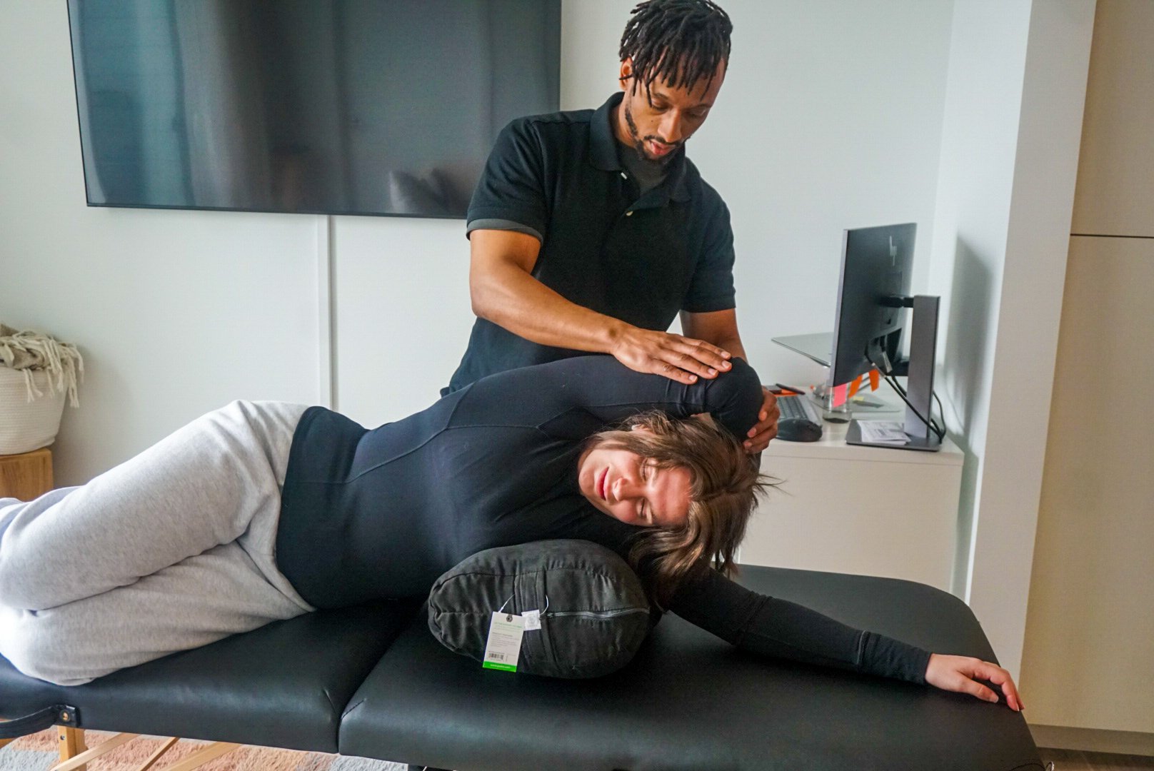 Coach performing assisted stretch therapy on a client at Rooted Fitness Collective