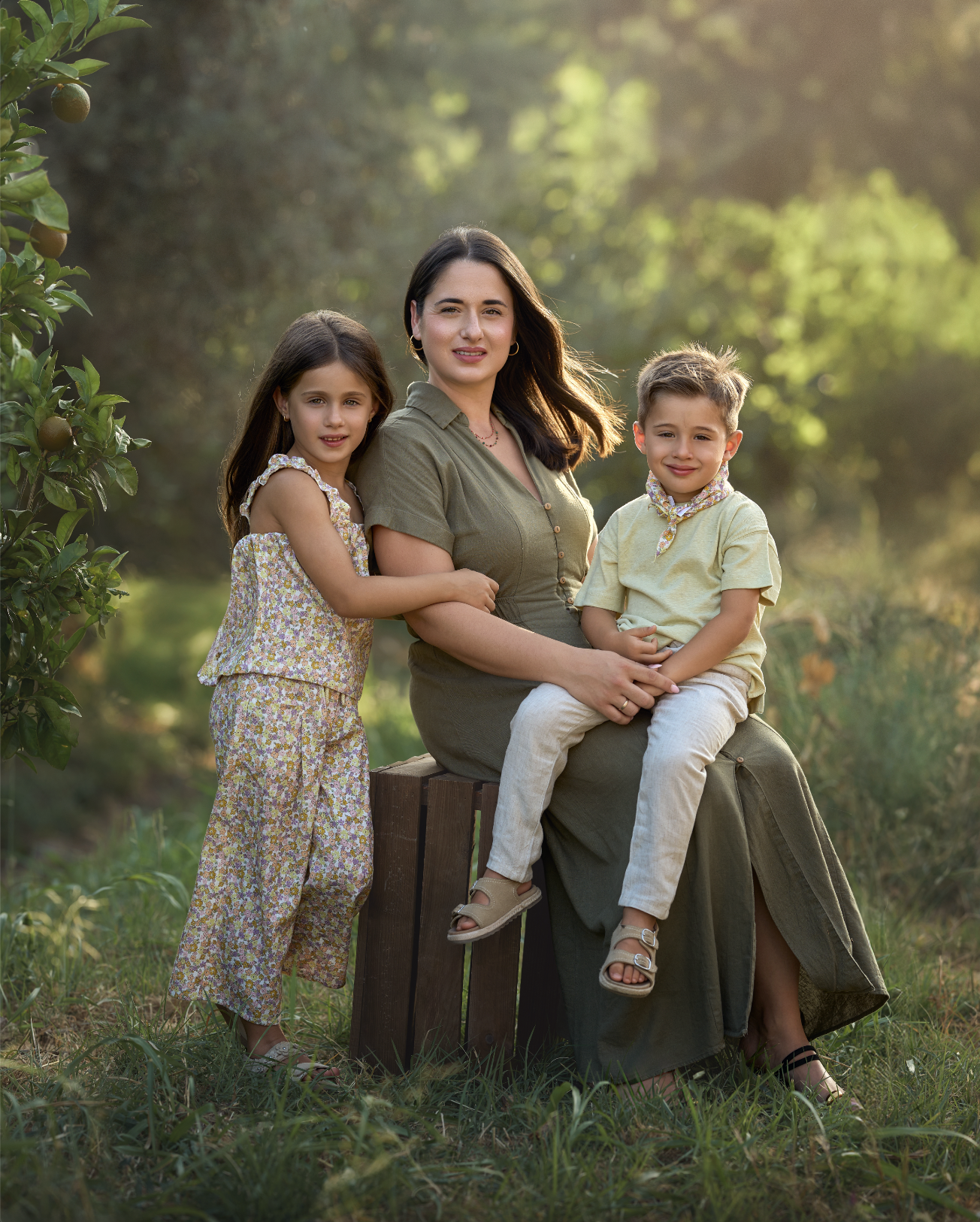 Mujer con dos niños en un entorno natural con árboles y luz suave
