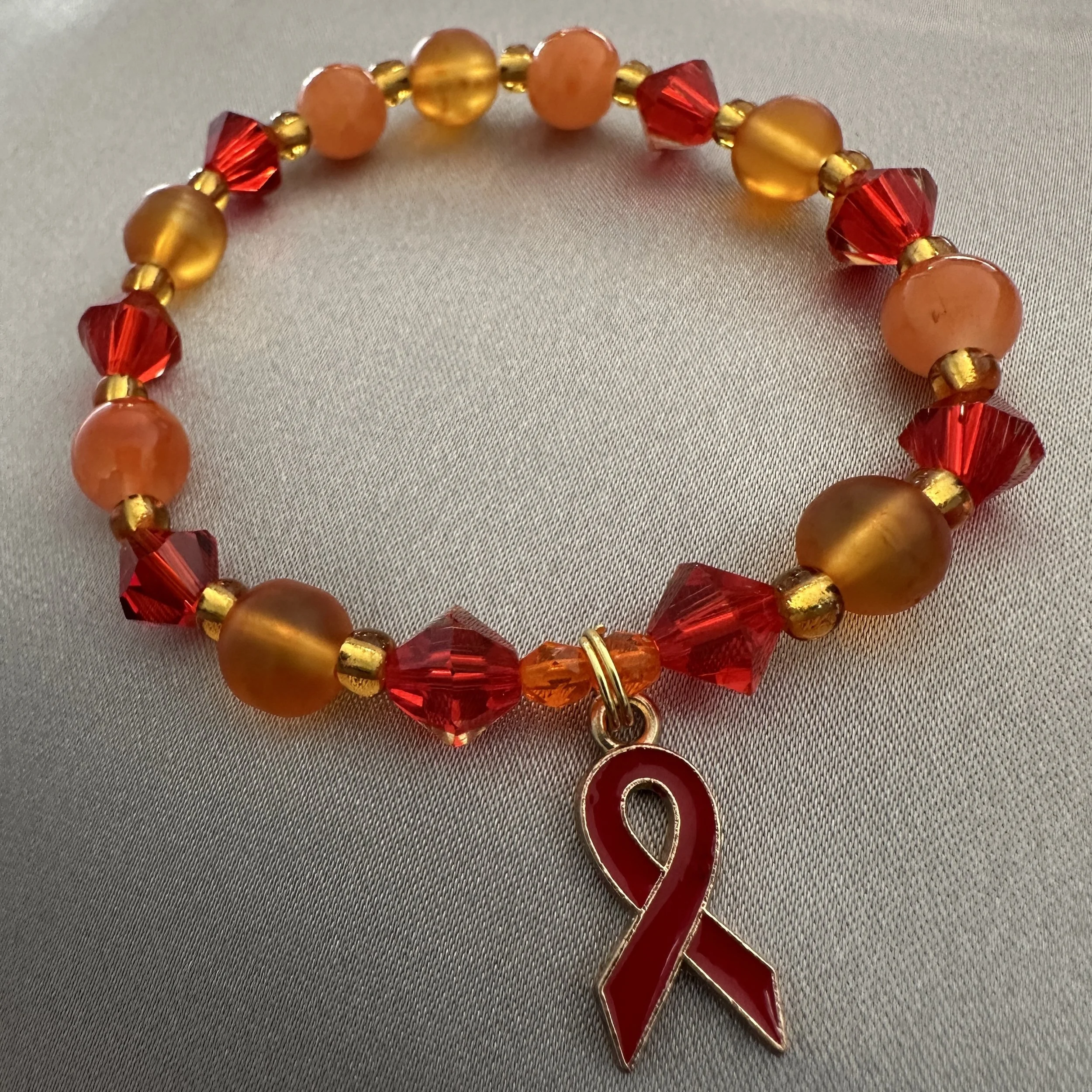 Red and Orange Beaded Bracelet W/Red Ribbon Charm
