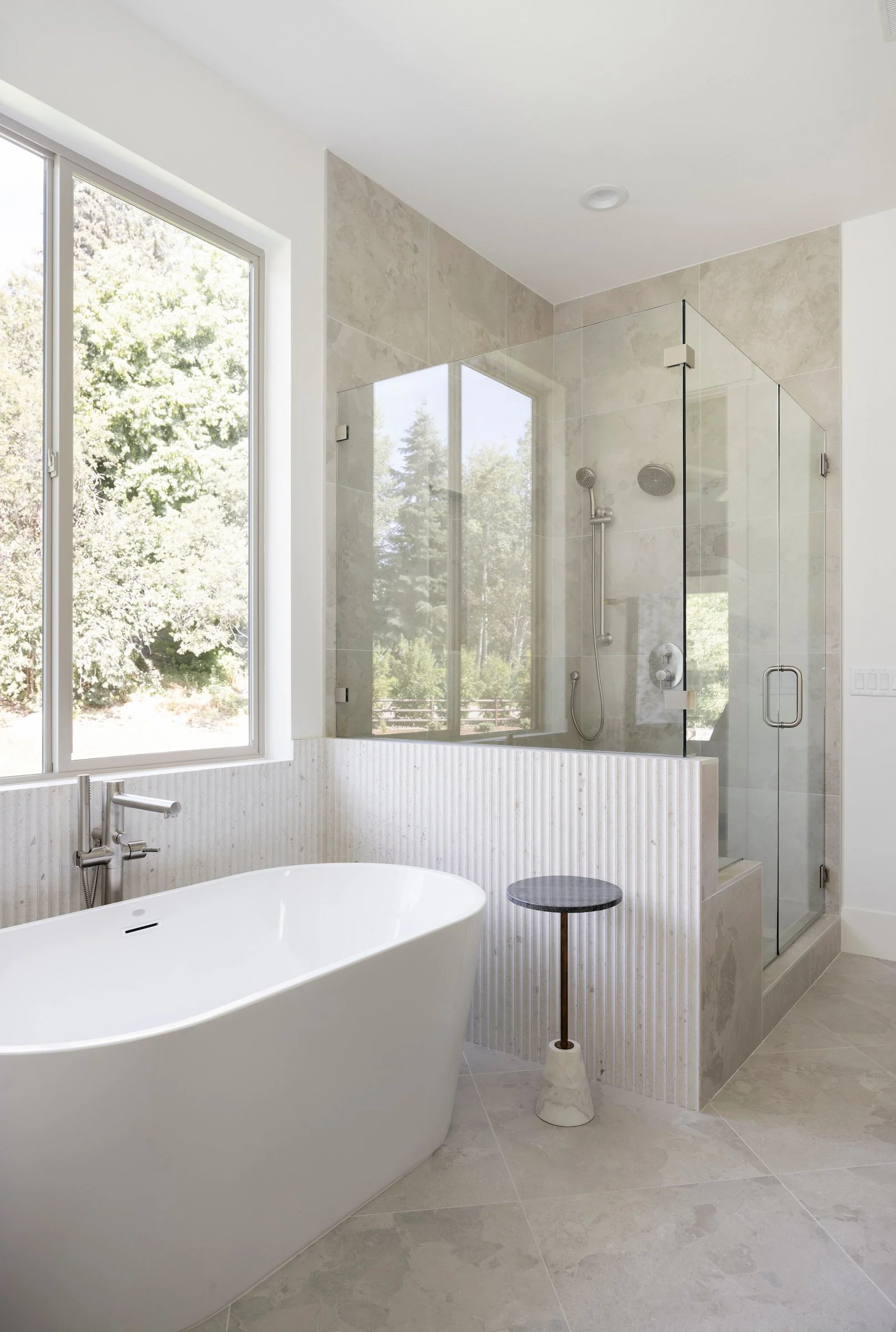 Modern luxury primary bathroom featuring a freestanding soaking tub and glass walk-in shower in a Gordon Milar Construction home