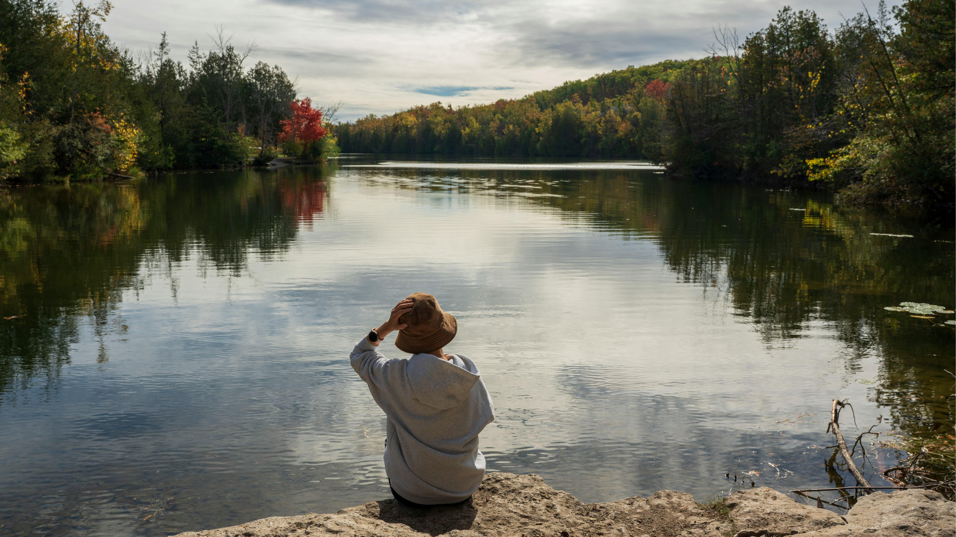 someone sitting on the edge of a still lake