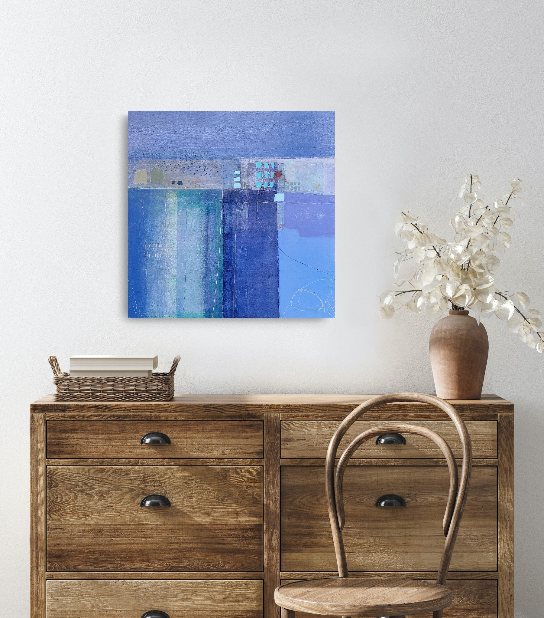 Blue painting on a wall above a chest of drawers