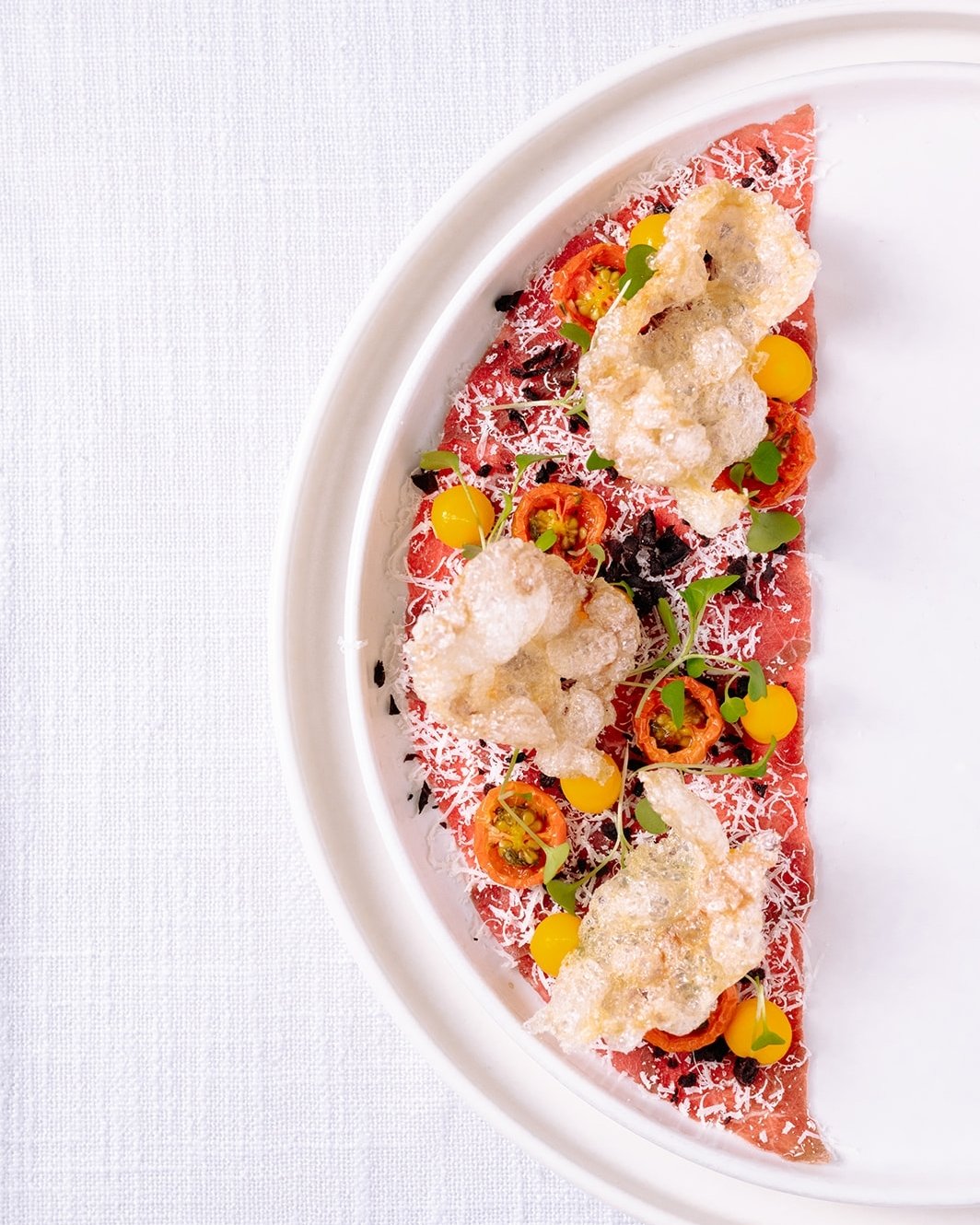 So. Beautiful. 😍
Our Prairie Ranchers organic beef carpaccio is a true work of edible art &mdash; delicate, flavourful, and crafted with intention.

Layered with truffle yolk emulsion, oven-dried tomato, kalamata olive crumb, puffed beef chips, peco