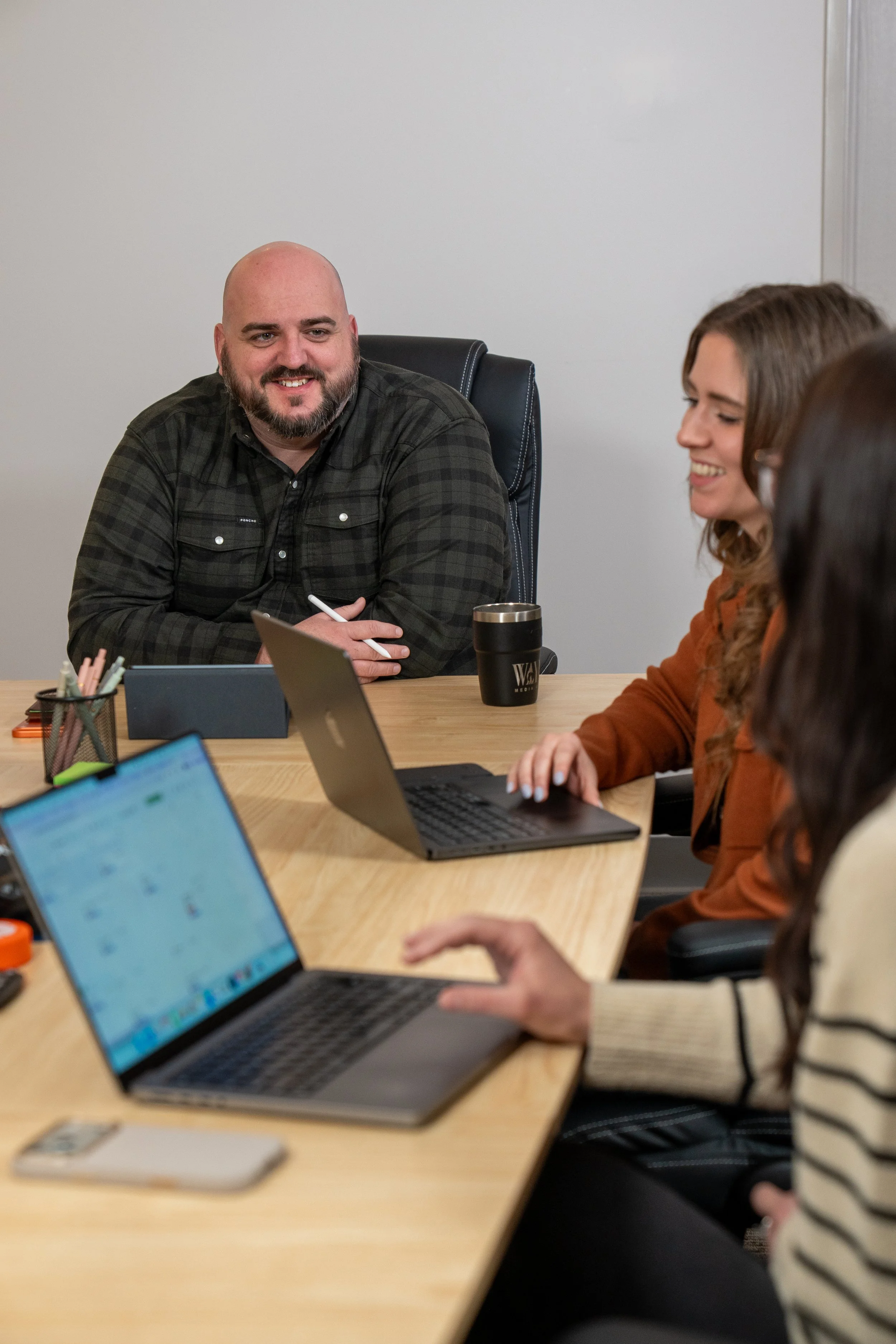 Small group gathered around a  conference table with laptops on the table .