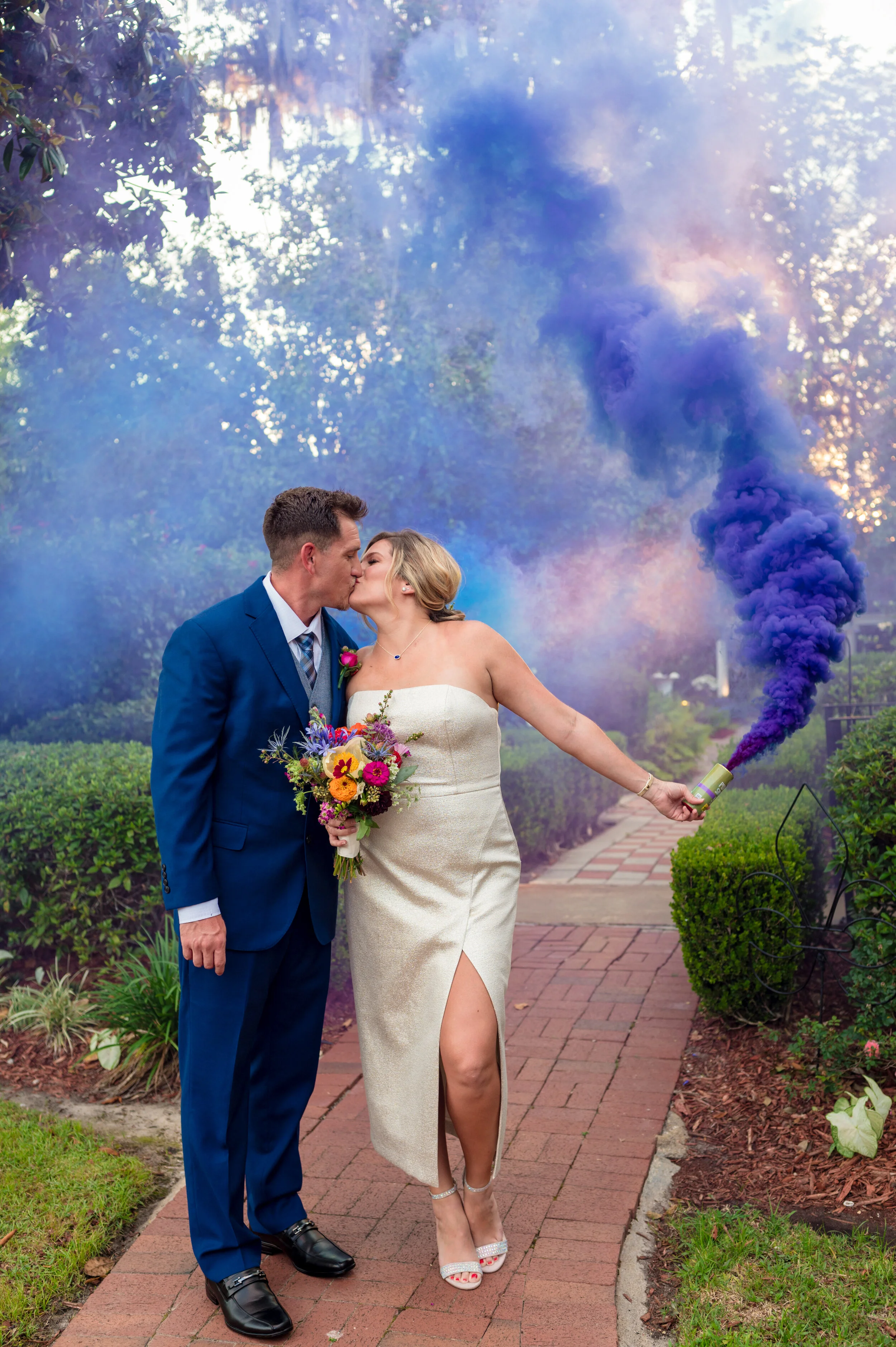 Newlyweds kissing with colorful smoke bombs 