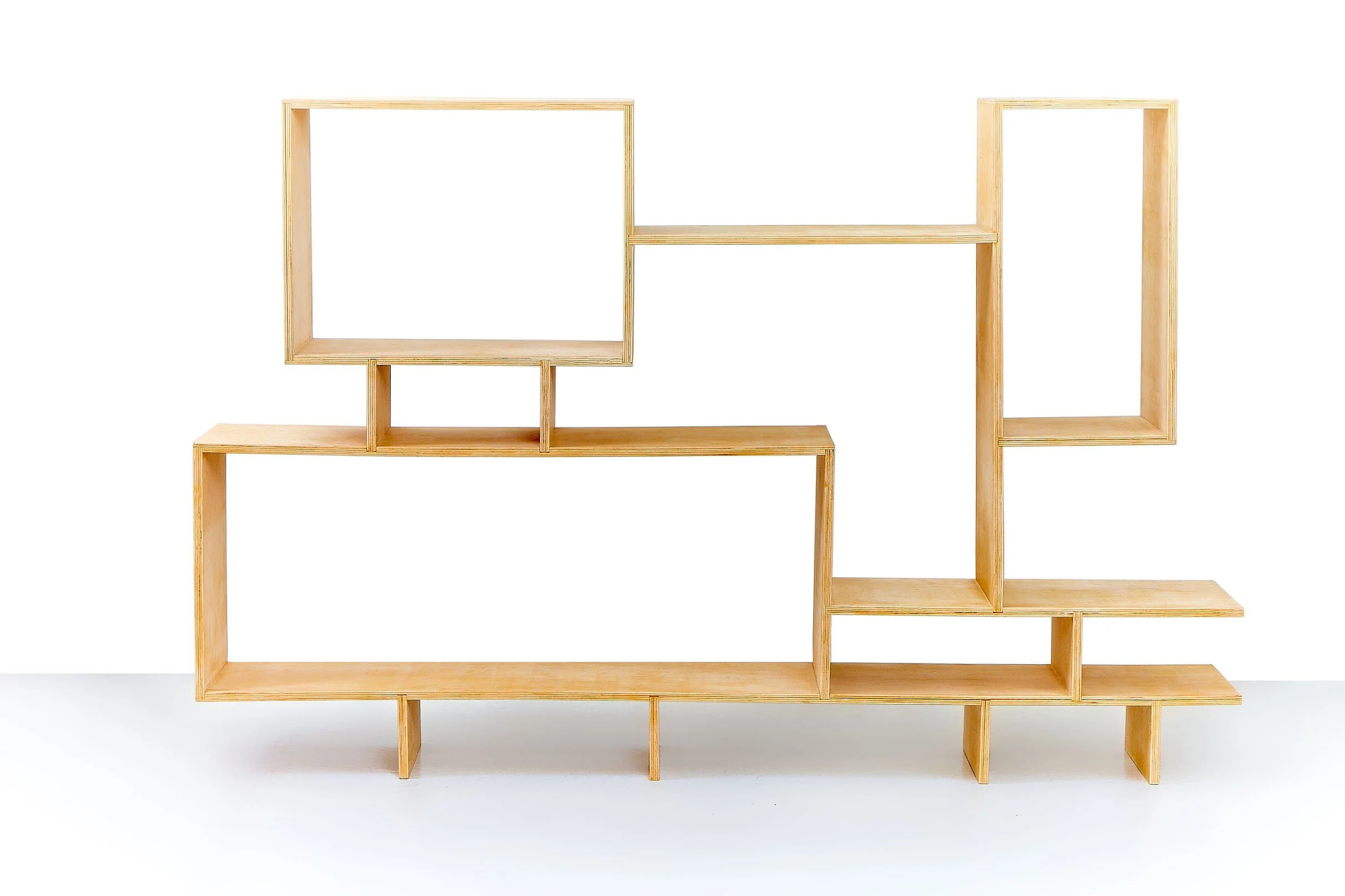 A modern, multi-level wooden bookshelf with open compartments, set against a white background.