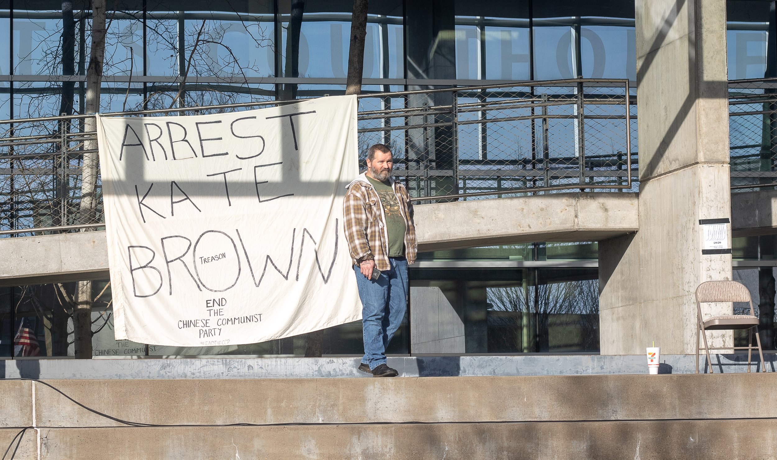 A protester stands on the steps of the Eugene Federal Courthouse, in front of a banner calling for the arrest of Oregon governor Kate Brown. A pro-Trump rally was held at Wayne Morse United States Courthouse in Eugene, Ore., on Jan. 9, 2021, in respo