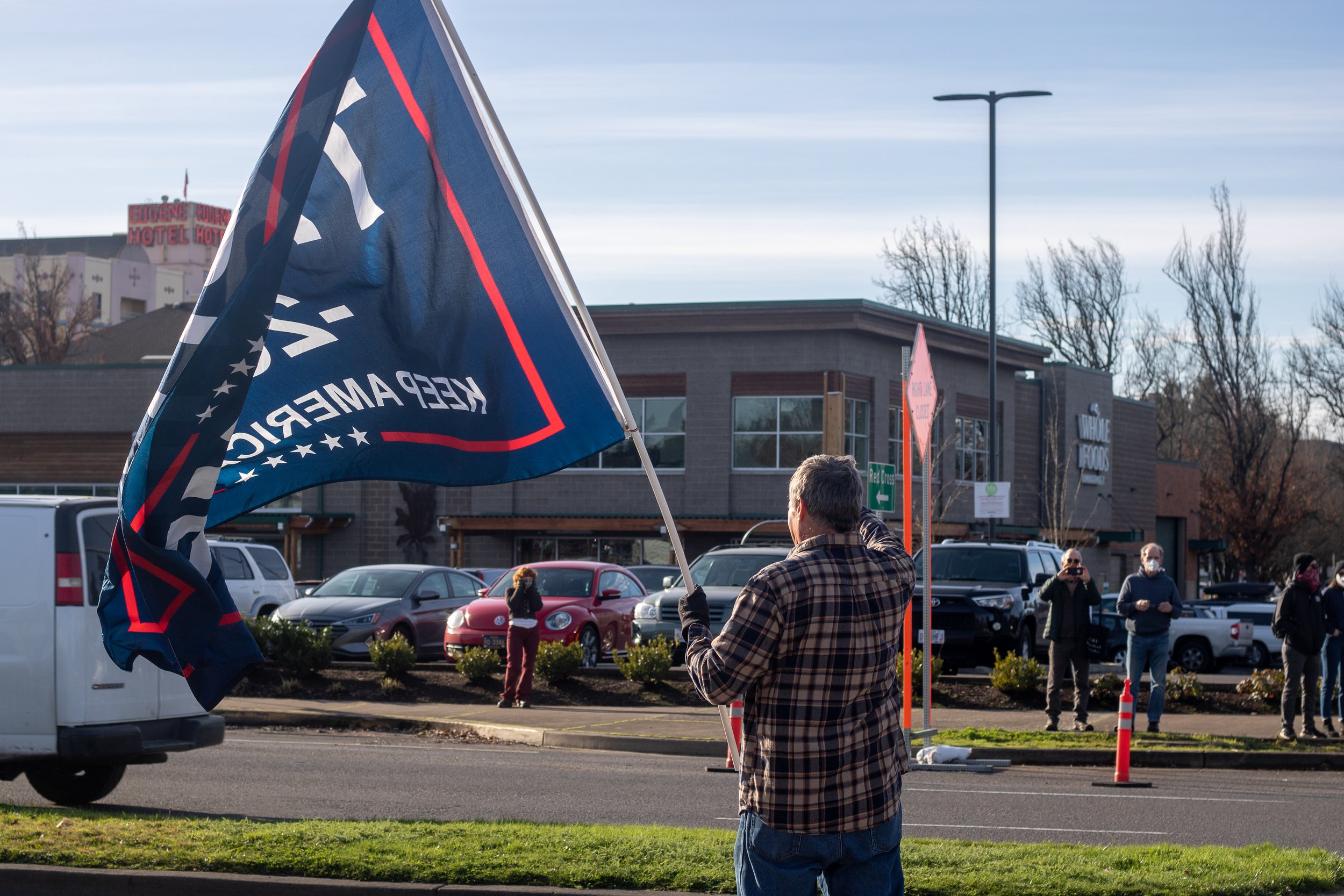 A protester waves a flag towards the crowded intersection of 8th and Broadway. A pro-Trump rally was held at Wayne Morse United States Courthouse in Eugene, Ore., on Jan. 9, 2021, in response to the riot that took place at U.S. Capitol earlier in the