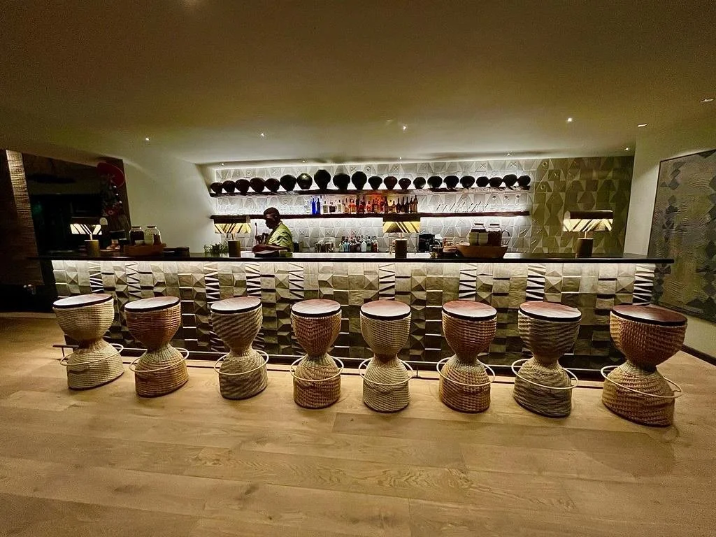 Bar — Completed build
Pattern, rhythm and sculpted surfaces

The completed bar retains these recognisable forms. The lighter bar front and simpler woven stool finishes create a different material expression from the rendered proposal.