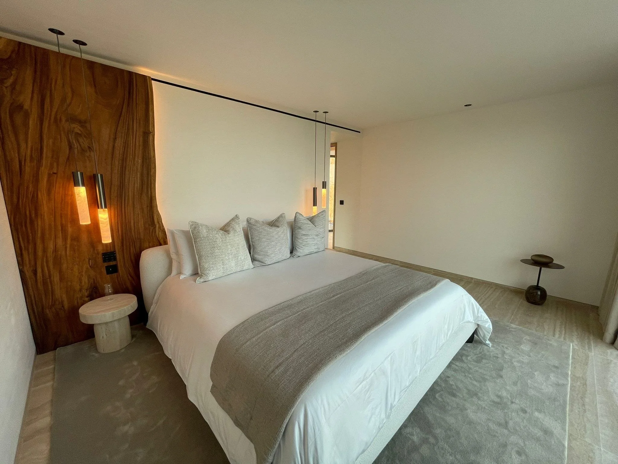 Main Bedroom — Completed build
A feature wall with a quiet palette

The site photograph shows the timber feature, warm pendant lighting and pale bedding carried through. Bedside furniture and styling differ from the rendered proposal.