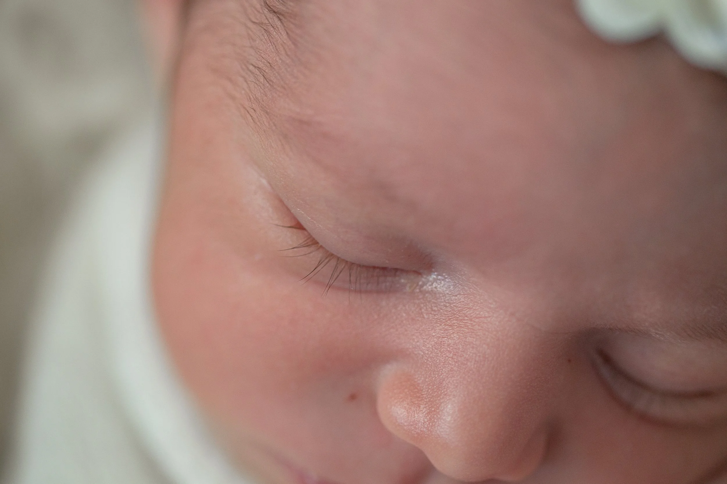 Close-up of a sleeping baby's face, focusing on closed eyes and soft skin.
